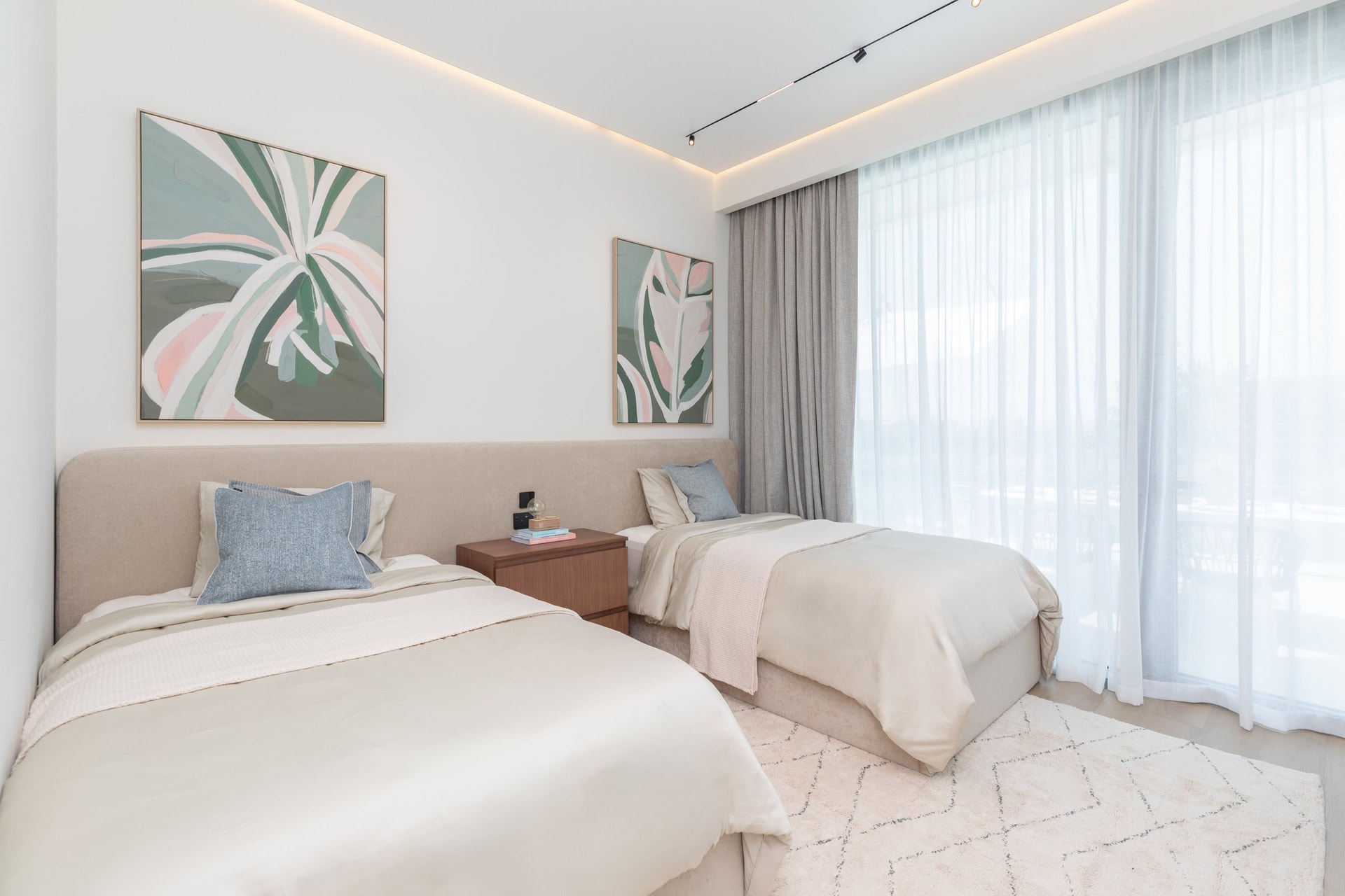 The second bedroom takes a softer line, with botanical canvases in muted greens and pinks