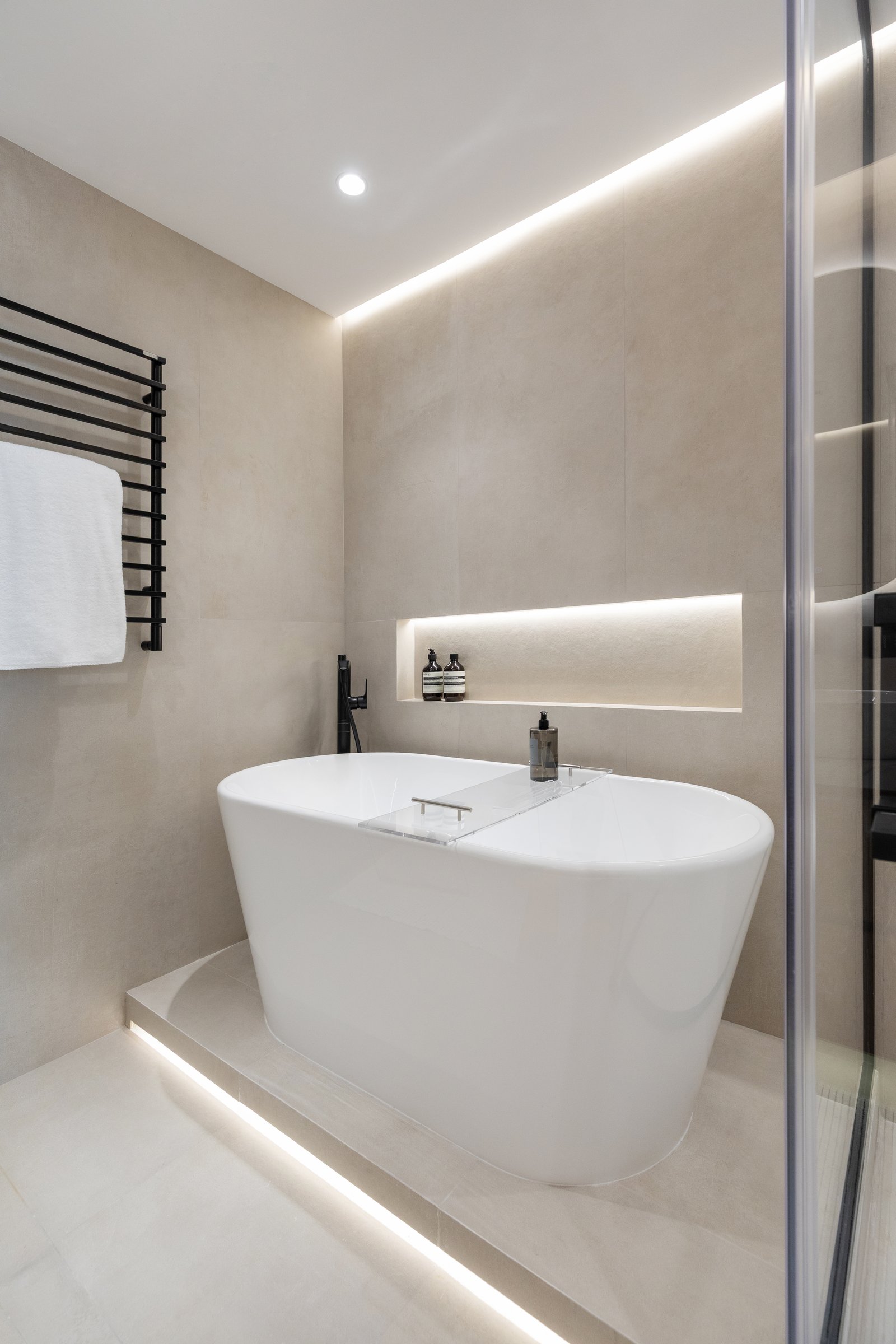 The bath sits raised on a tiled plinth and backlit from below, so the tub appears to hover