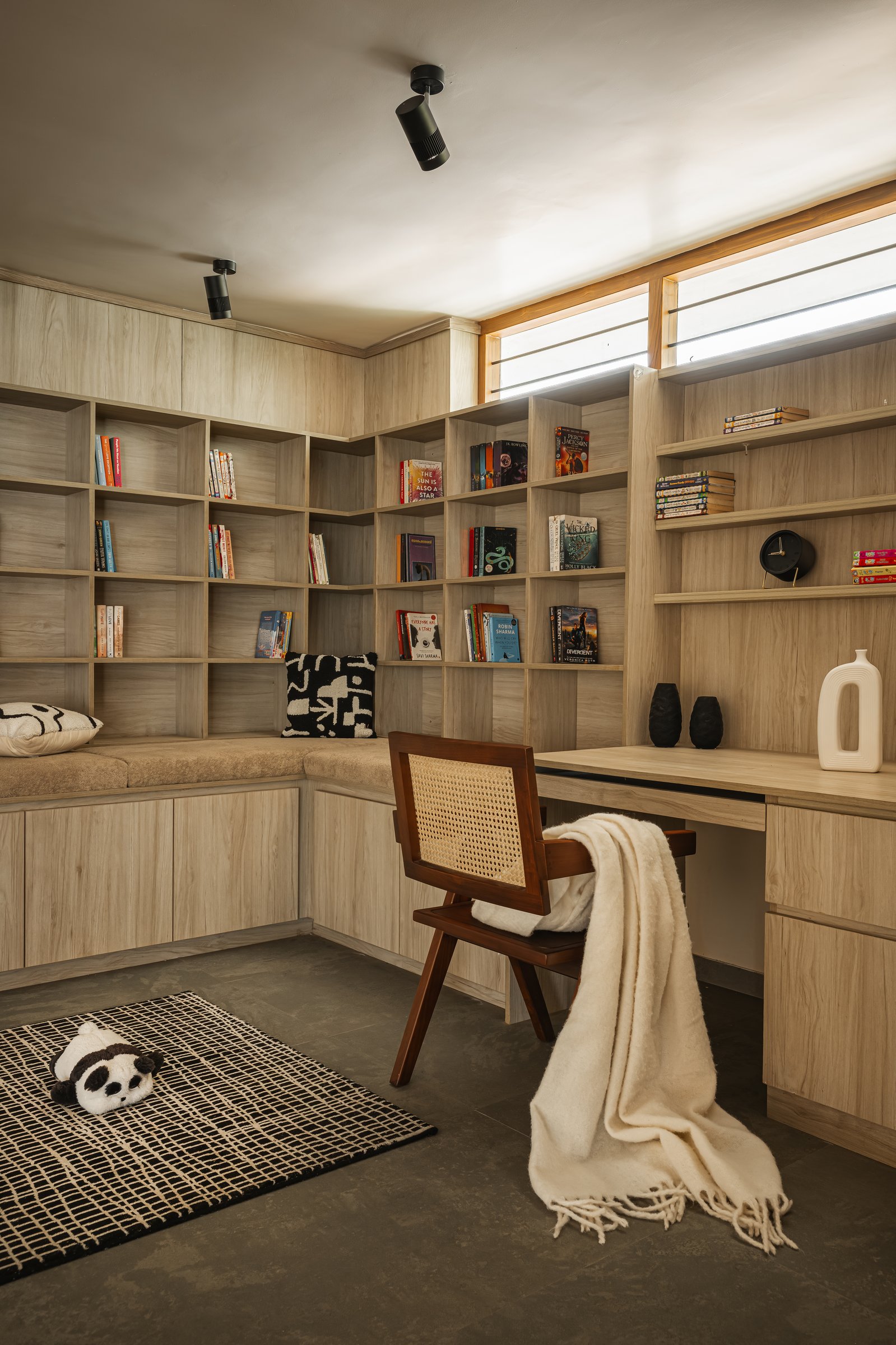 The library nook, held to a single tonal family of pale ash joinery so the books themselves provide the colour