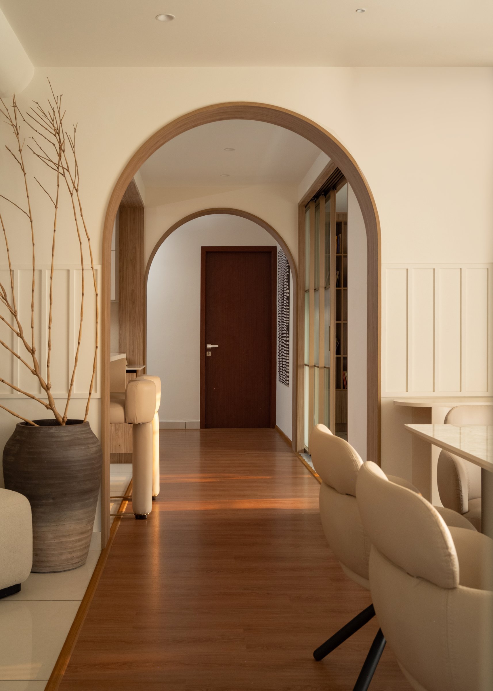 Nested arches compress the eye toward a dark wood door at the corridor's end