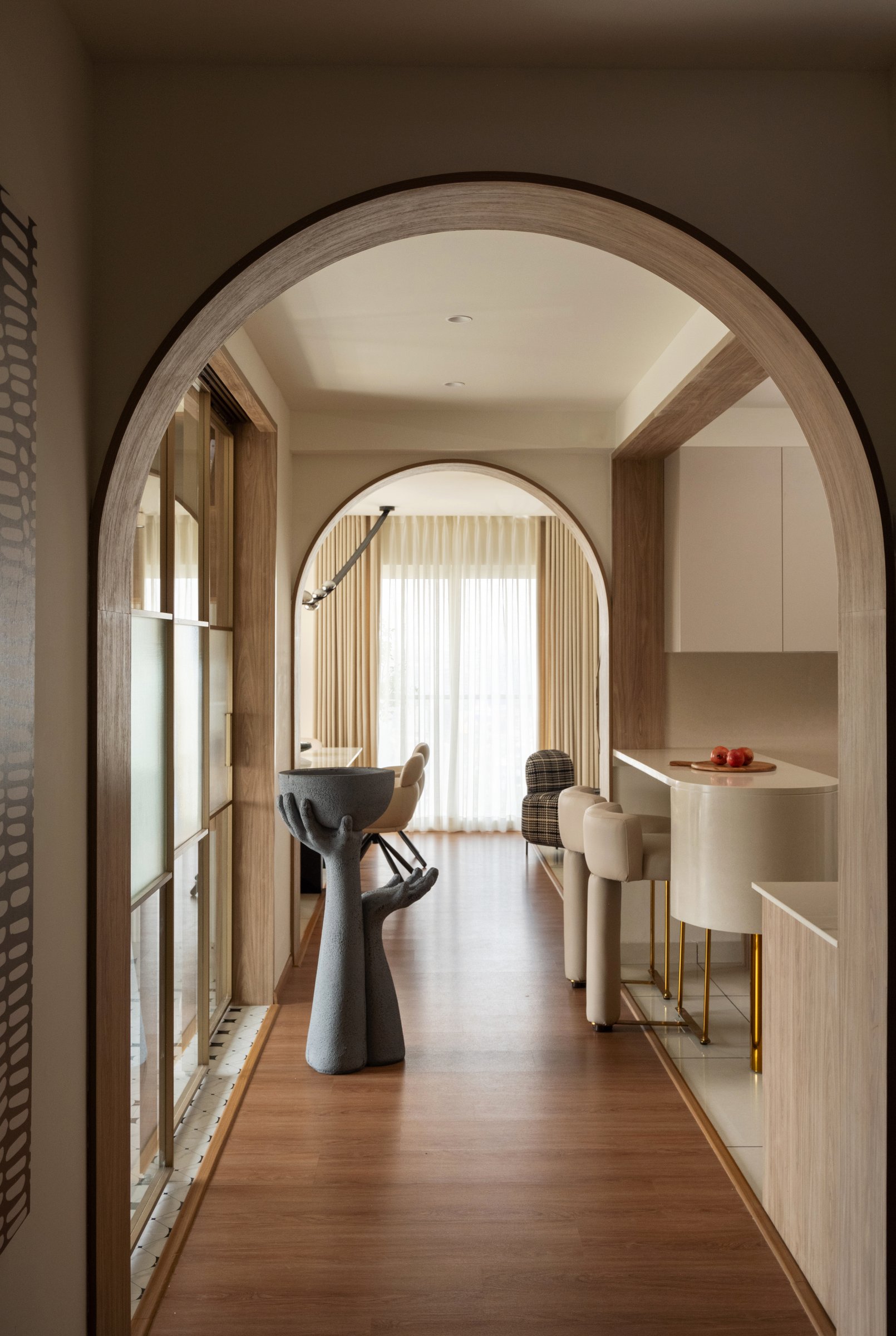 Telescoping arches from the multipurpose room back toward the kitchen, with a sculptural hand-form pedestal in the foreground