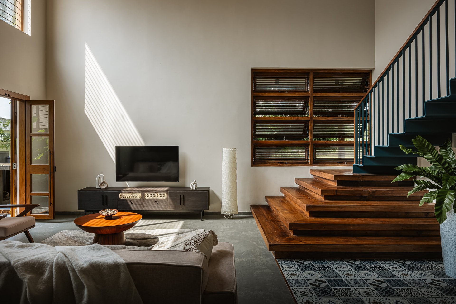 The living room, pared to its essentials and lit by a slatted wooden window that bands the wall in afternoon light