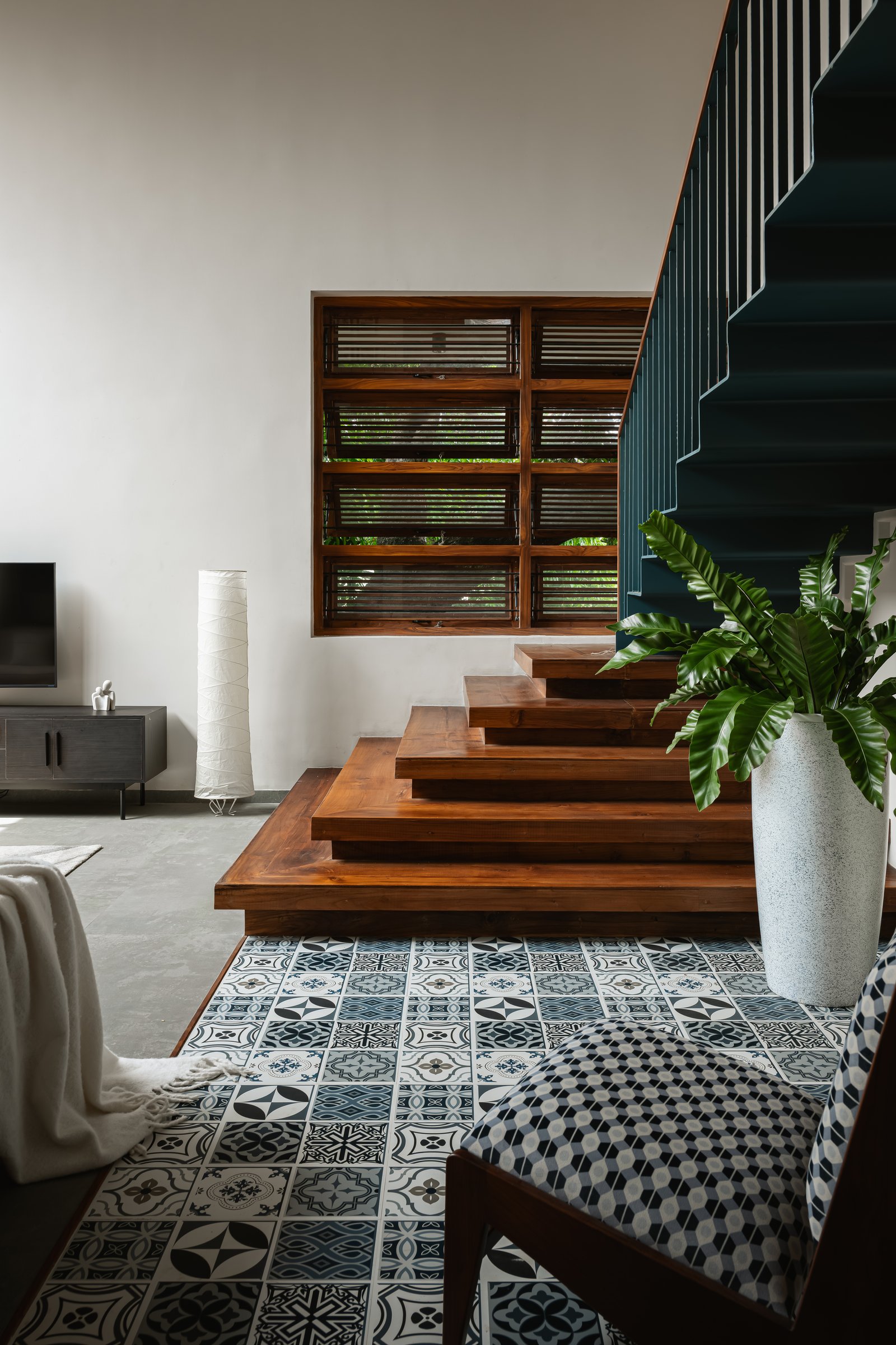 The base of the staircase doubles as informal seating, with the encaustic tile floor performing its quiet ordering work