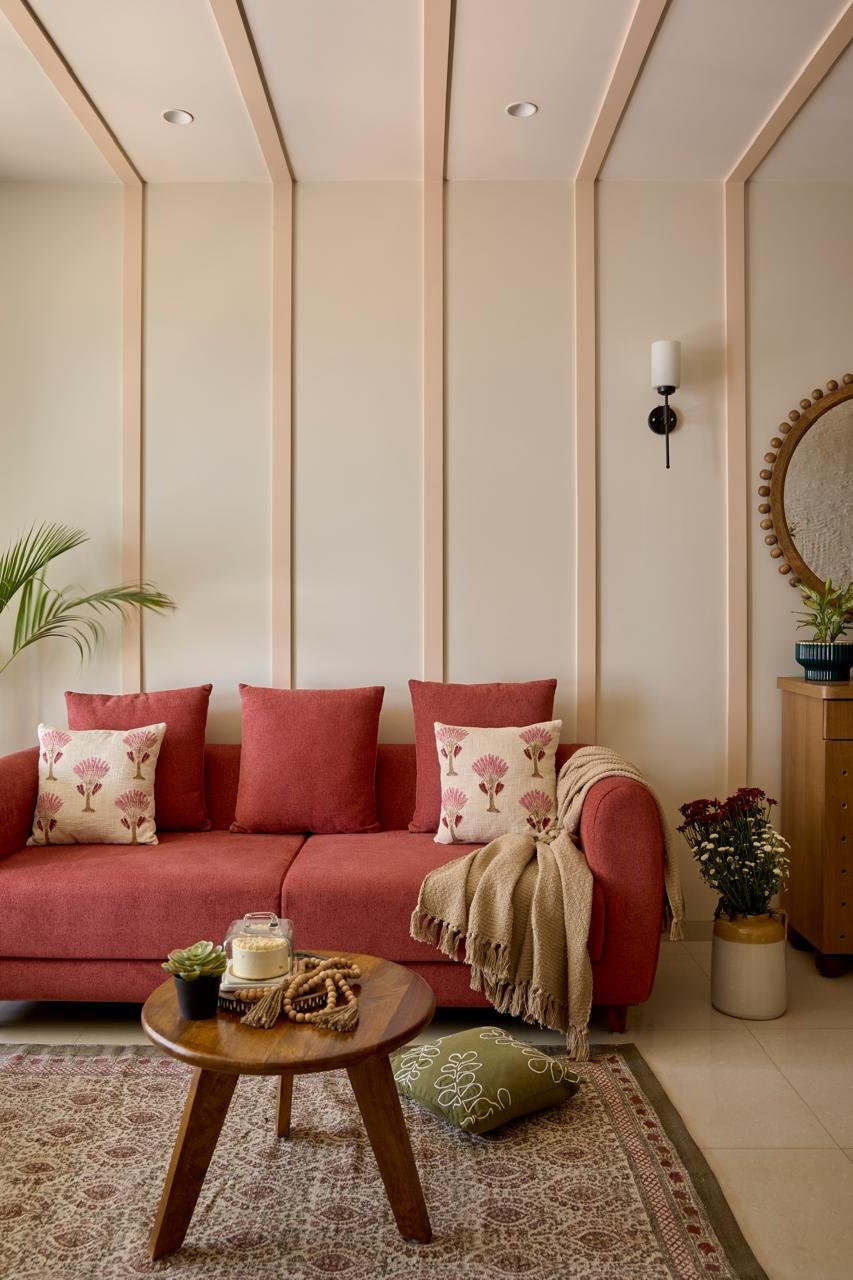 The living room, where a maroon sofa lands with deliberate weight against a calmly grooved peach-and-ivory wall