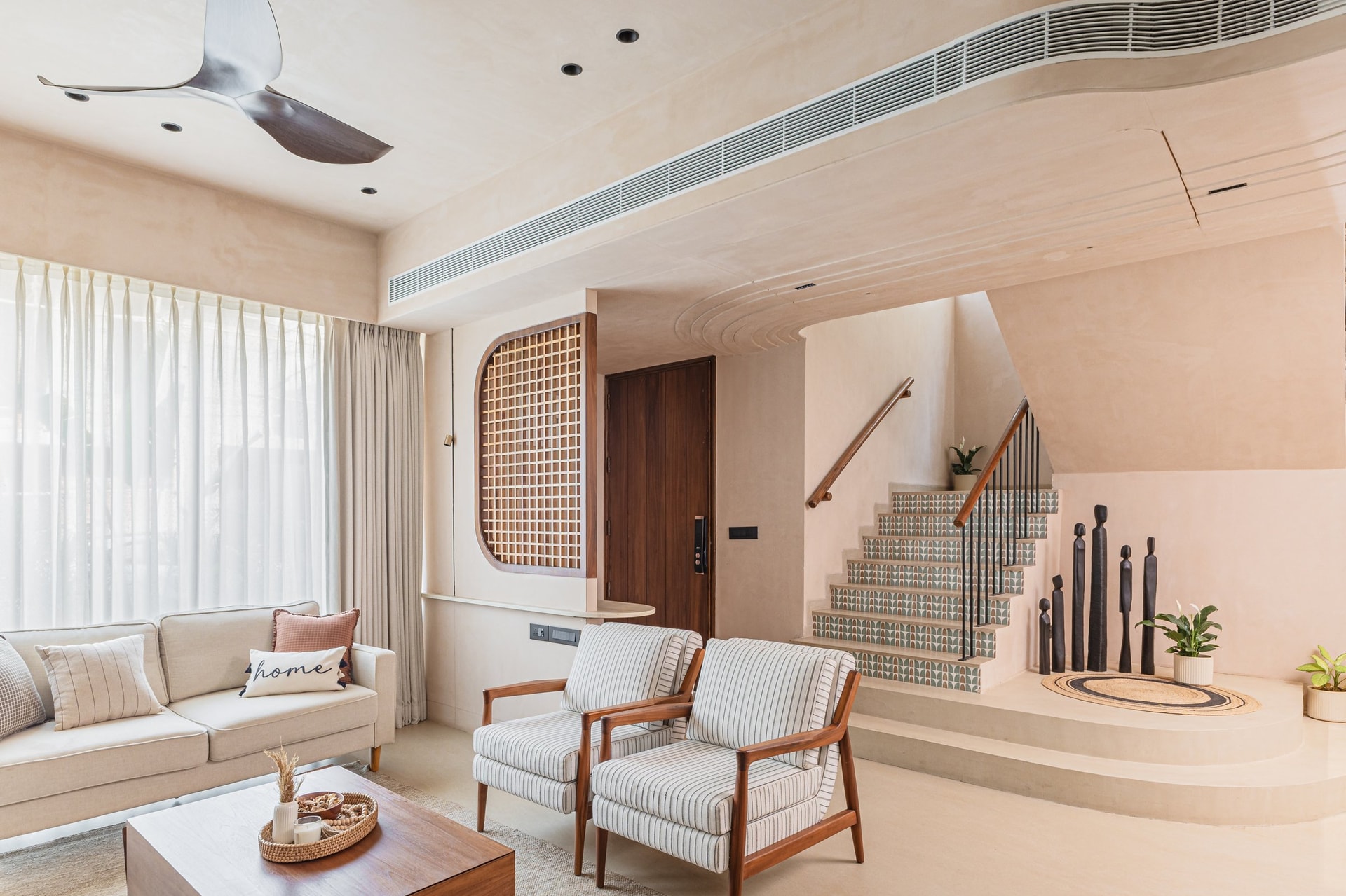The living room read against the staircase: an arched timber jaali anchors the room to its Vadodara setting