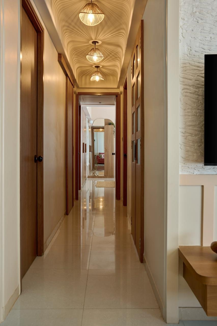 The internal corridor, where three woven rattan pendants and a turbulent ceiling shadow turn passage into choreography