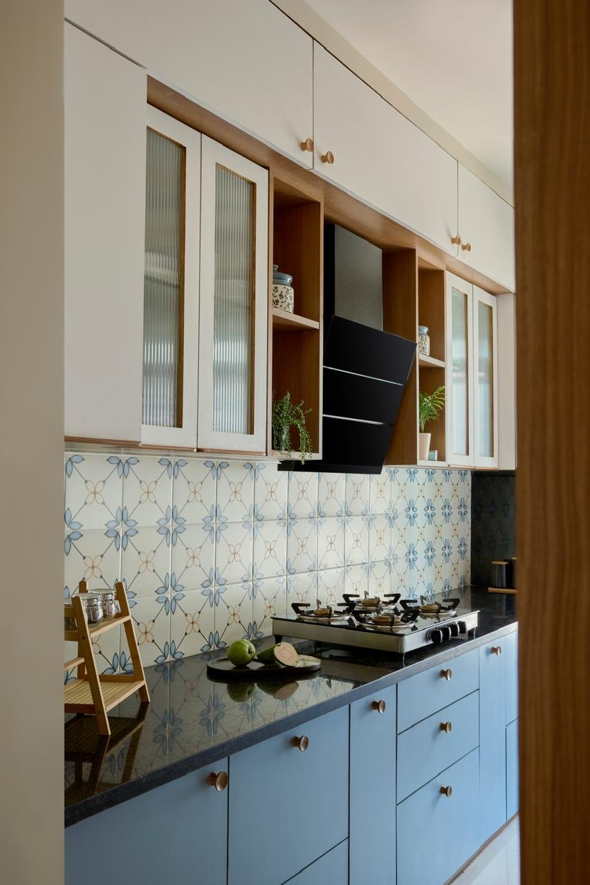The kitchen, where soft blue lowers and ivory uppers meet a hand-painted floral tile backsplash