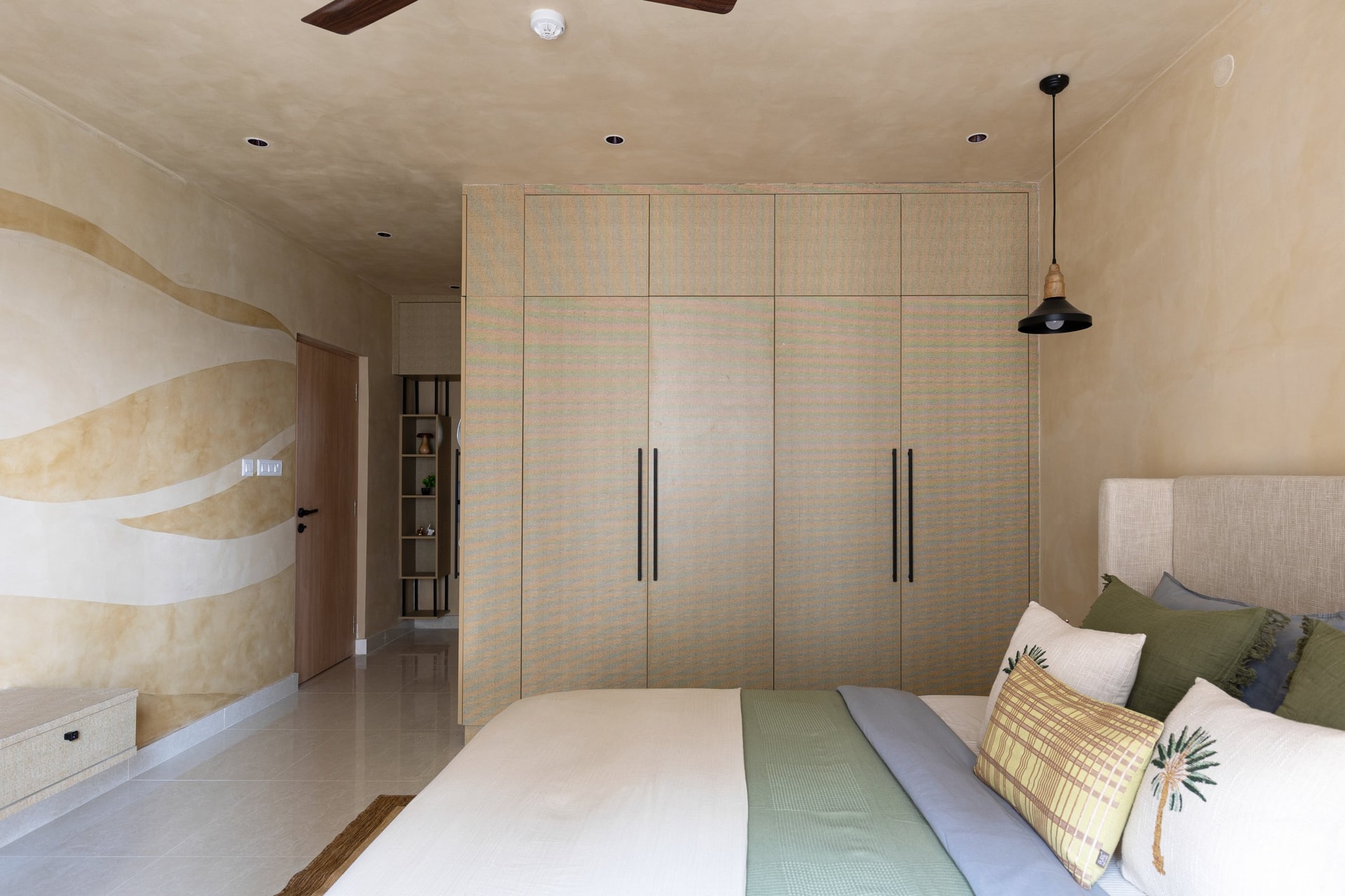 From the bed, a bank of wardrobes in a softly iridescent woven-textile finish closes the room