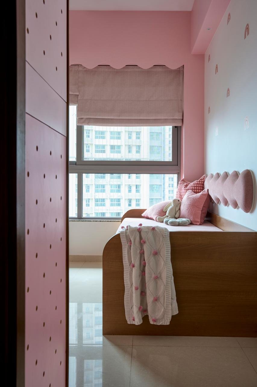 The daughter's bedroom, fully committed to pink with scattered rainbow motifs and a scalloped pelmet