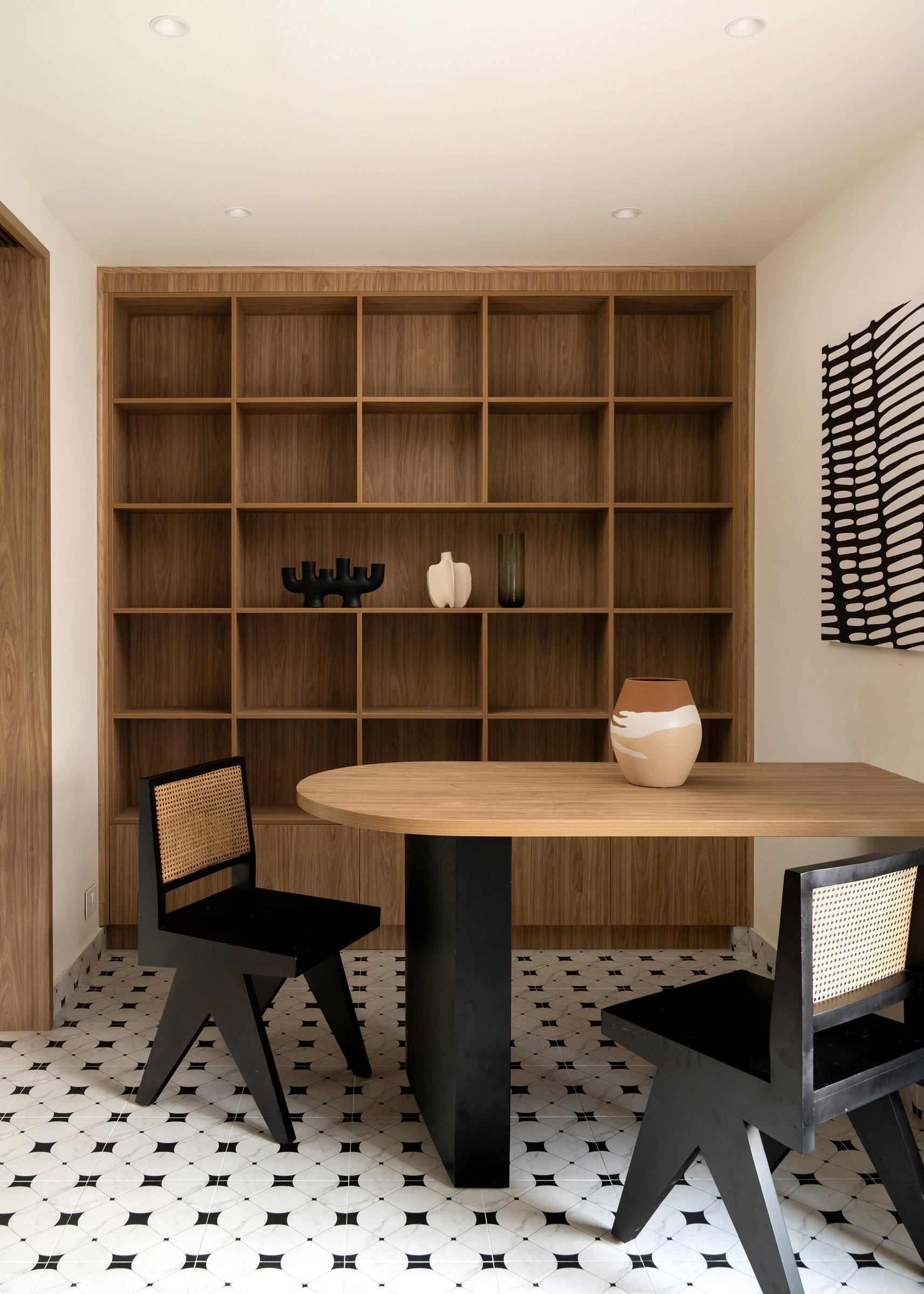 The multipurpose room: full-height wood-grid shelving, an oval table, and a shift to monochrome geometric tile