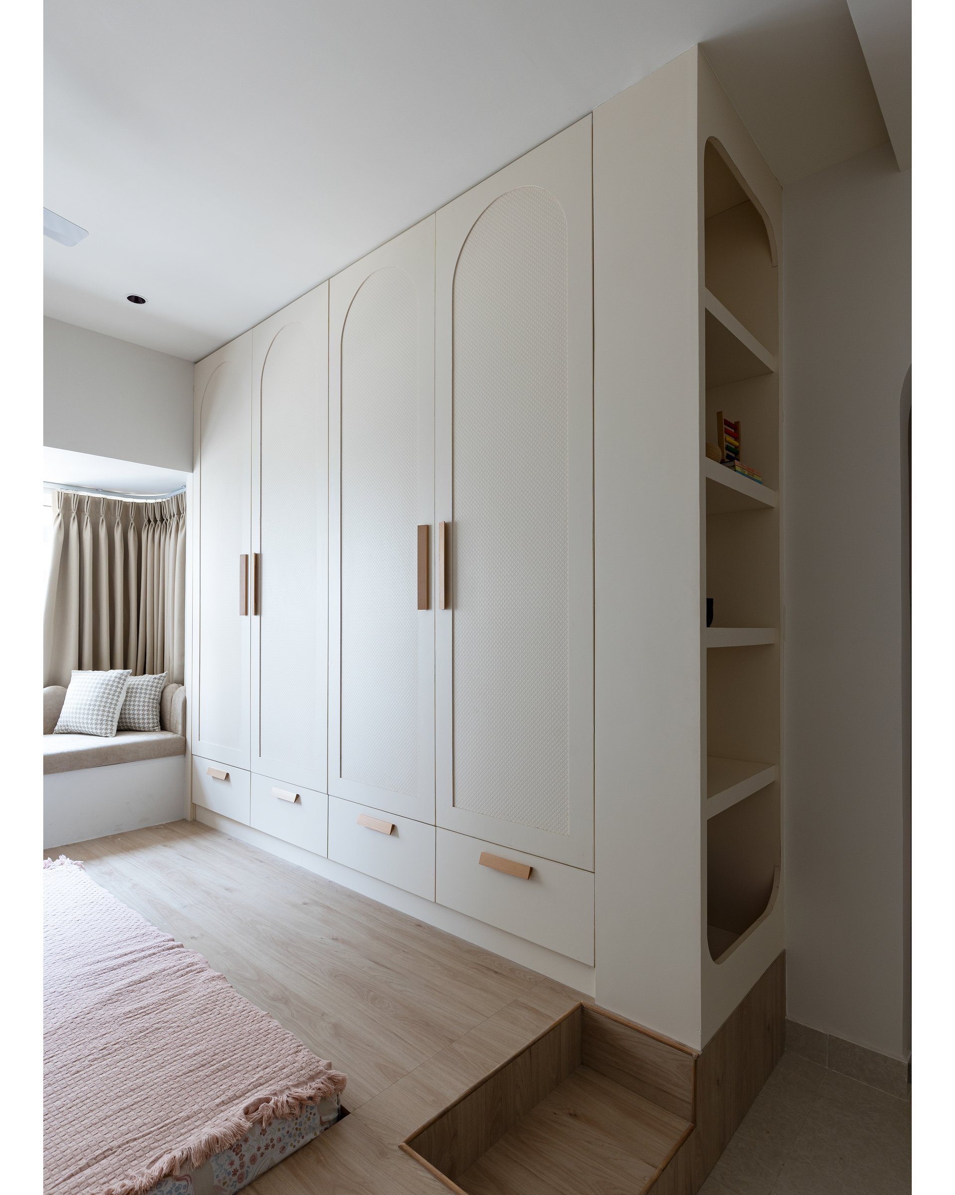 Arch-detailed wardrobes in chalky off-white, with leather pull-tabs as the only visible hardware