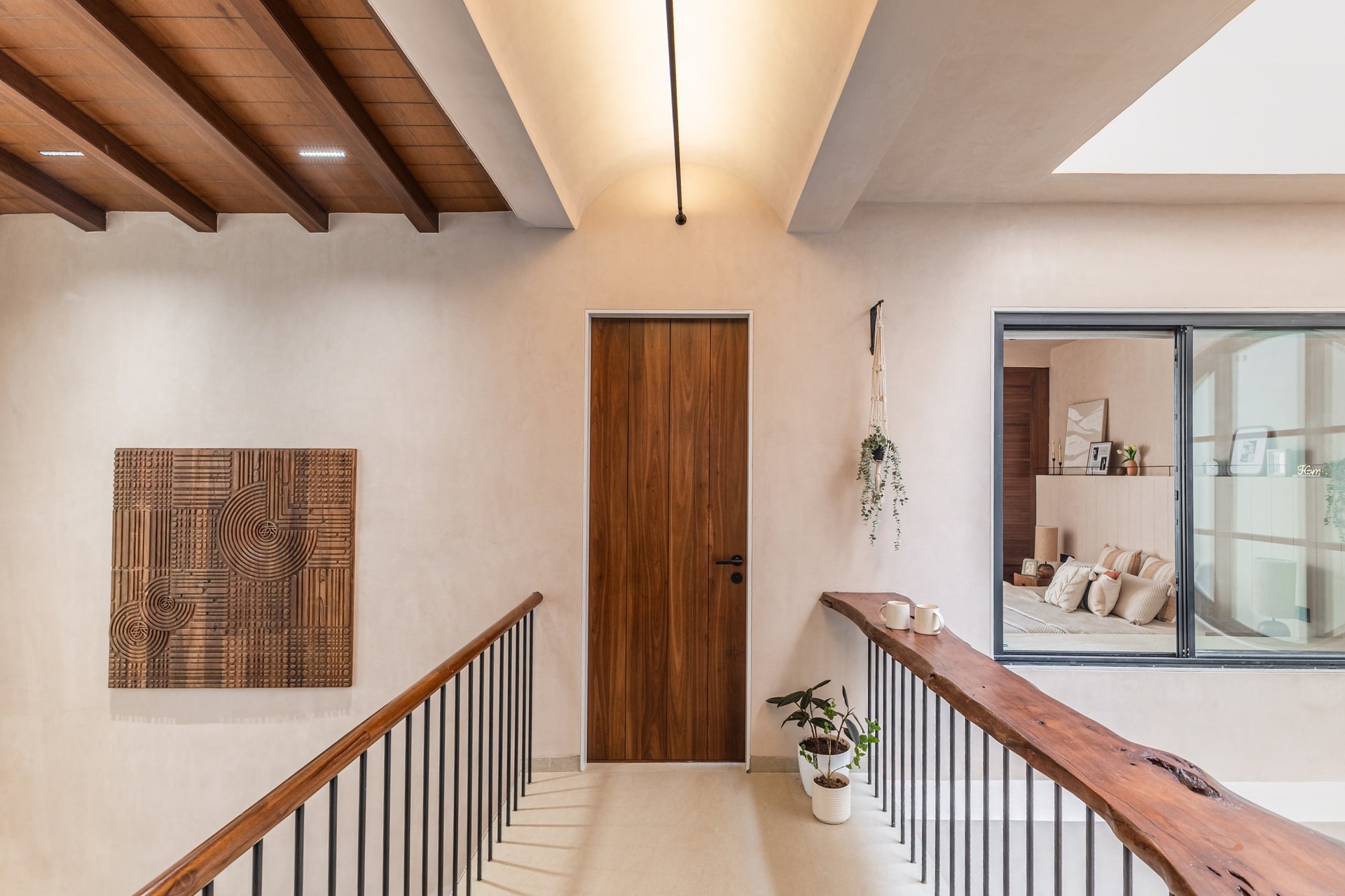 The upper passage: exposed wooden beams, a vaulted ceiling, and a live-edge handrail running the balustrade