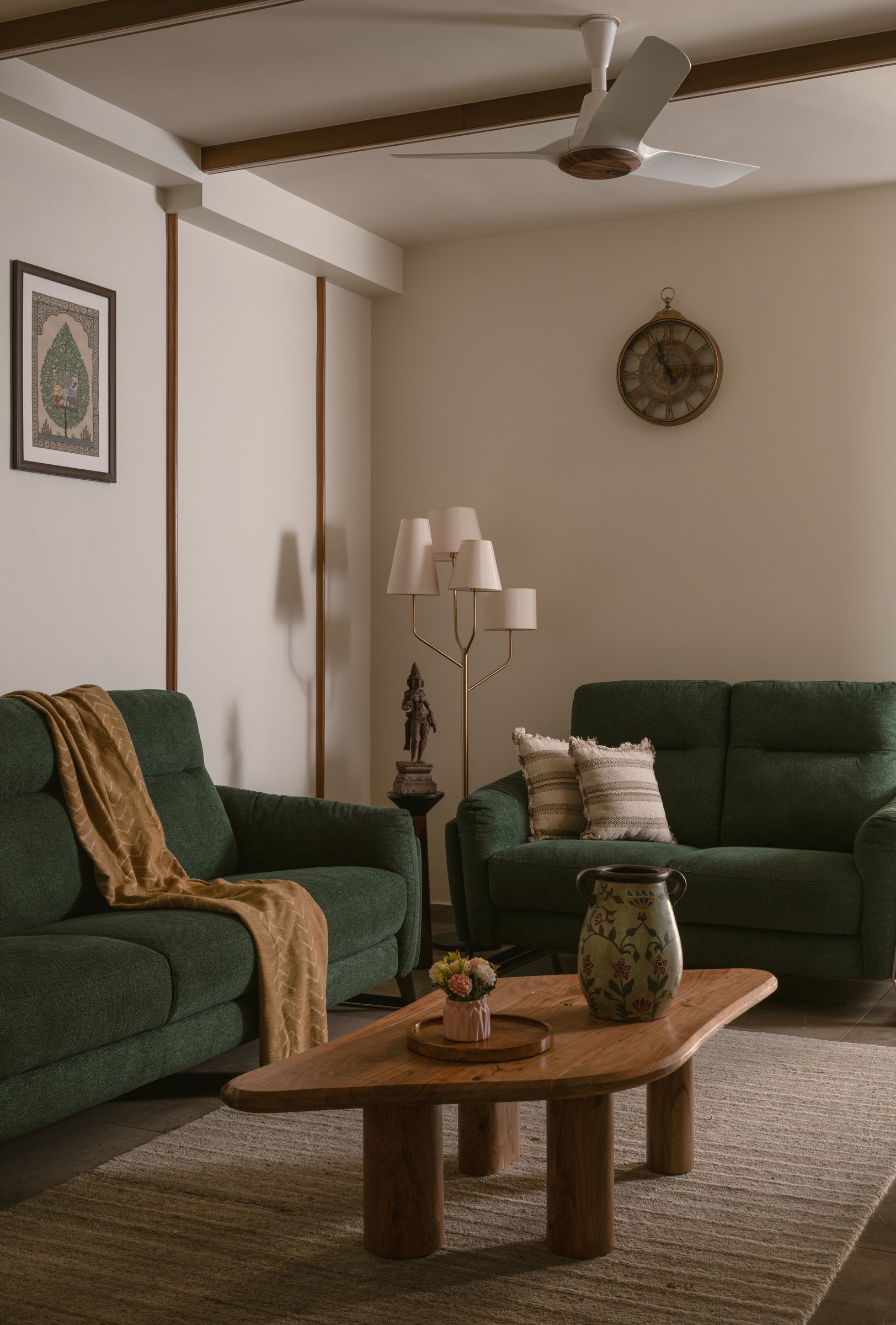 The living room in muted forest green, where slim wooden beams and vertical battens organise the space without dominating it