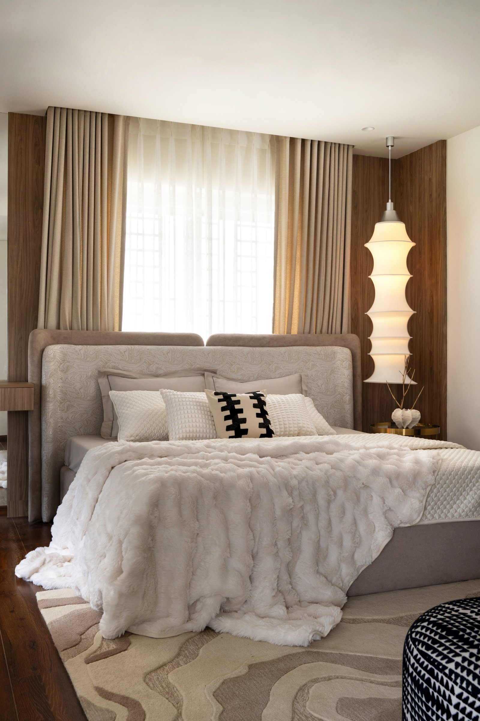 The master bedroom: a wood-clad headboard wall and a ribbed fabric pendant drop beside the bed