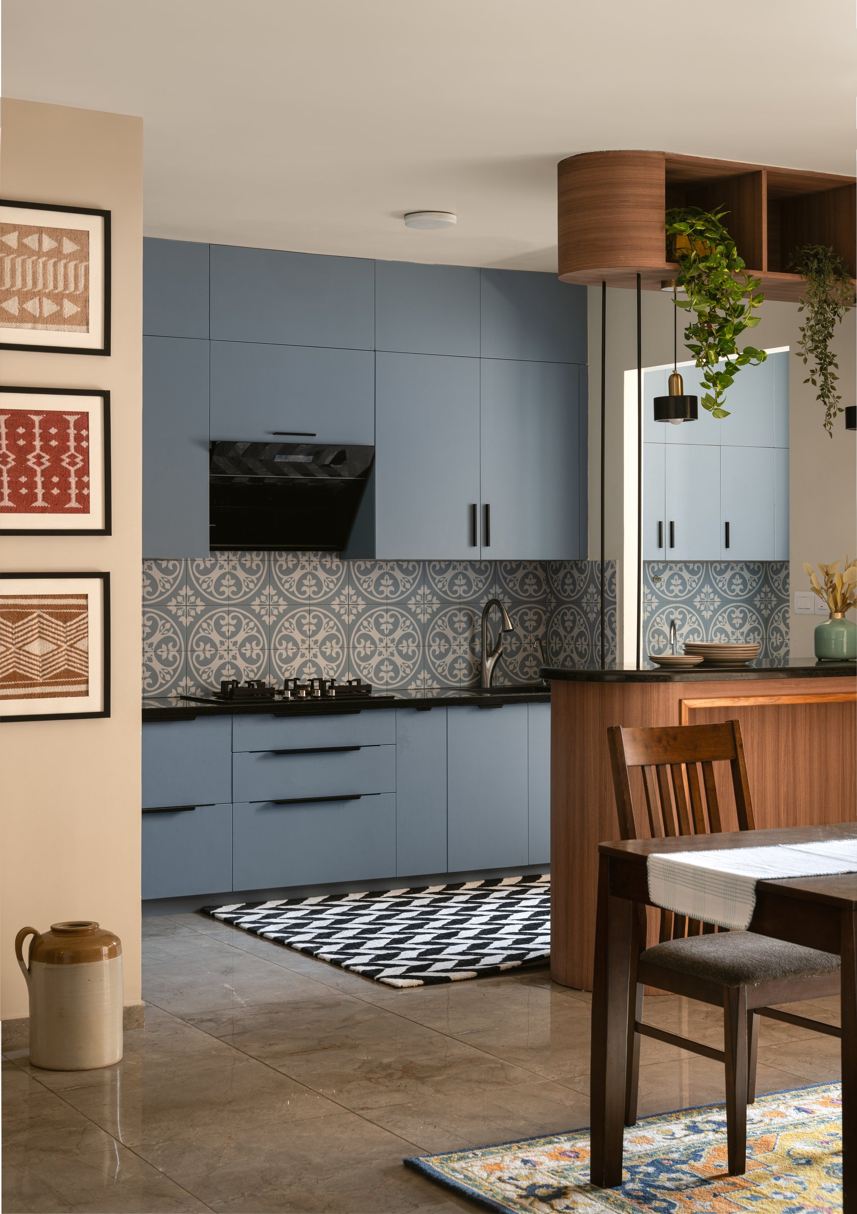 The kitchen in dusty blue, framed by a curved fluted wooden breakfast counter that softens the architectural edge