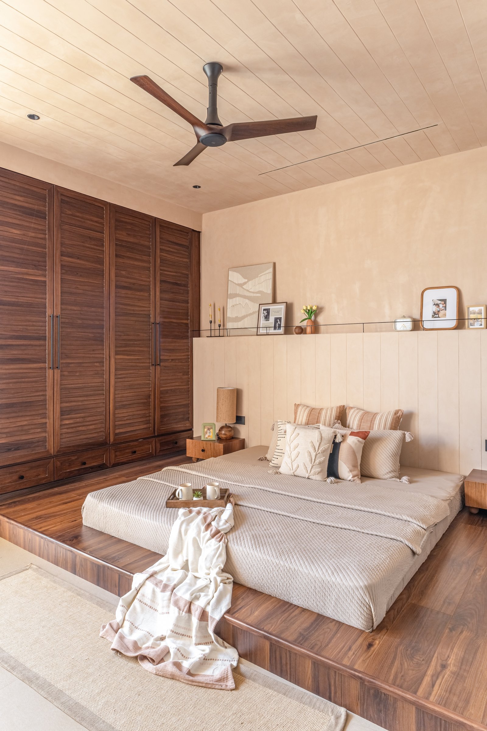 The master bedroom, where a panelled headboard wall and a wood-clad ceiling lower the room's apparent height