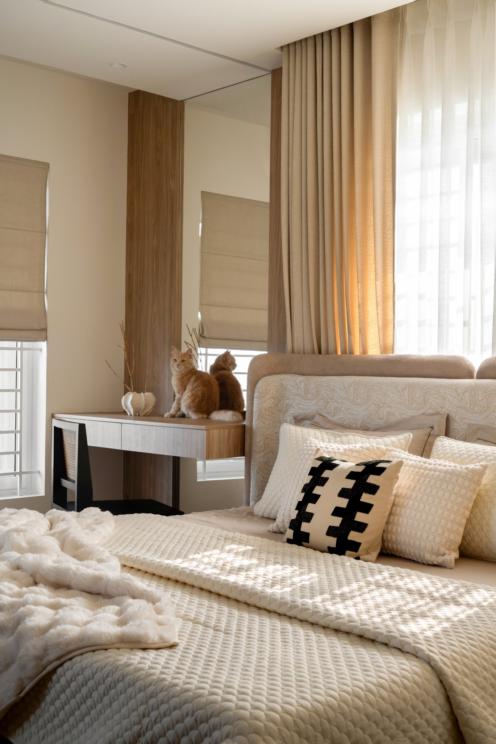 The dressing console alongside the bed, with linen Roman shades tempering the light