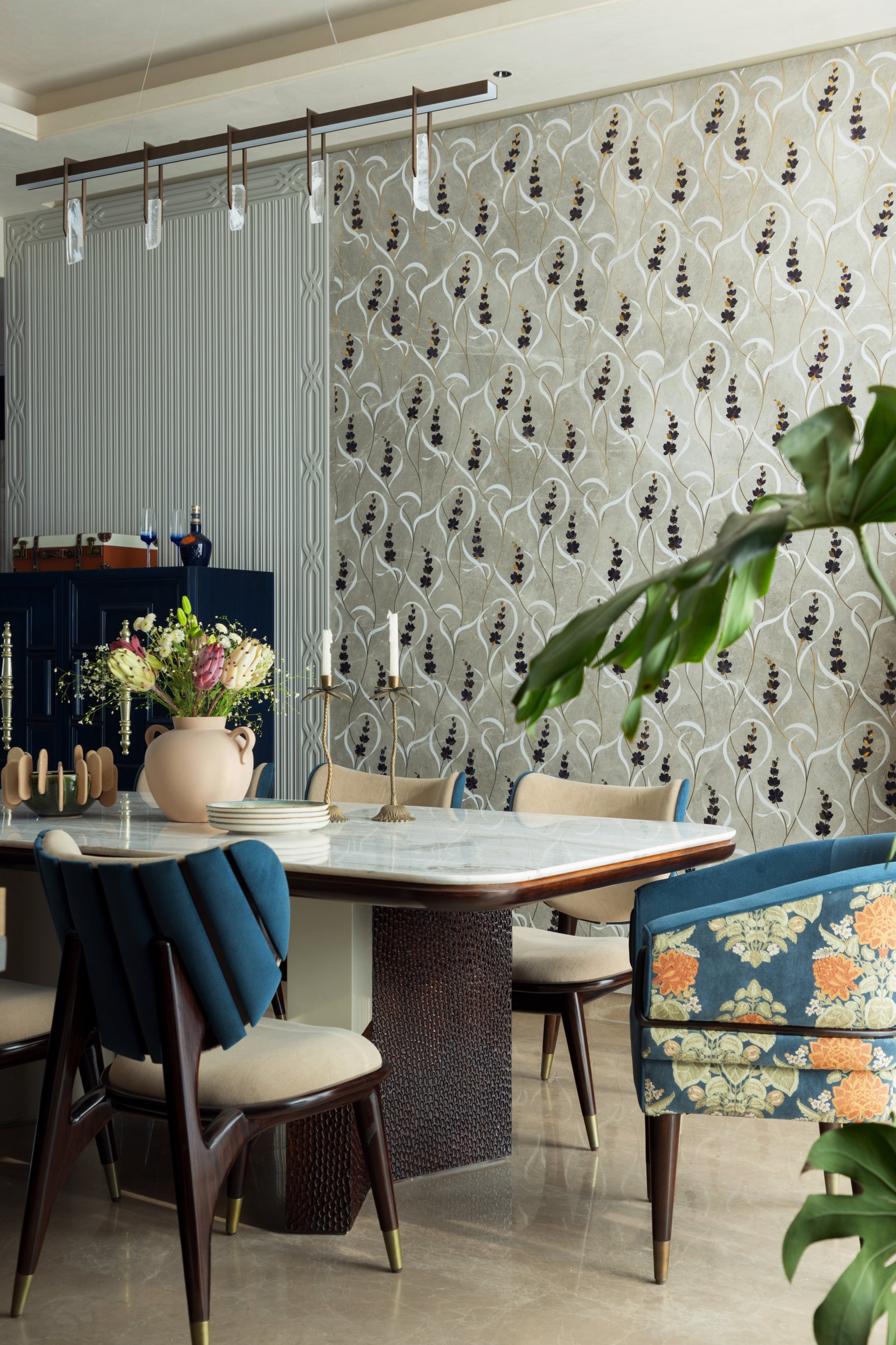 A closer view of the dining table's hand-textured pedestal and the suspended linear pendant with crystalline drops