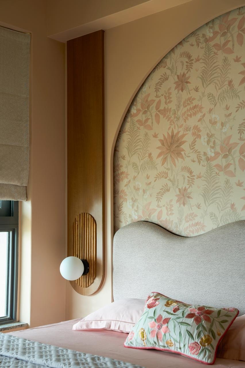 A detail at the headboard's edge: a reeded wooden pilaster anchoring a single round glass sconce