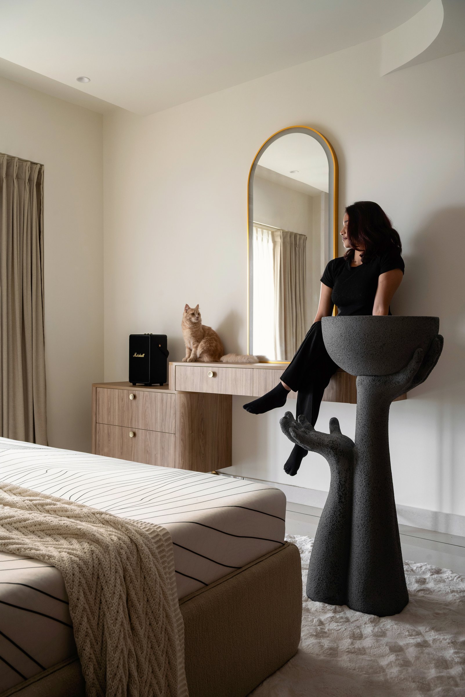 The dressing console with its arched brass mirror and cast-stone hand-form pedestal