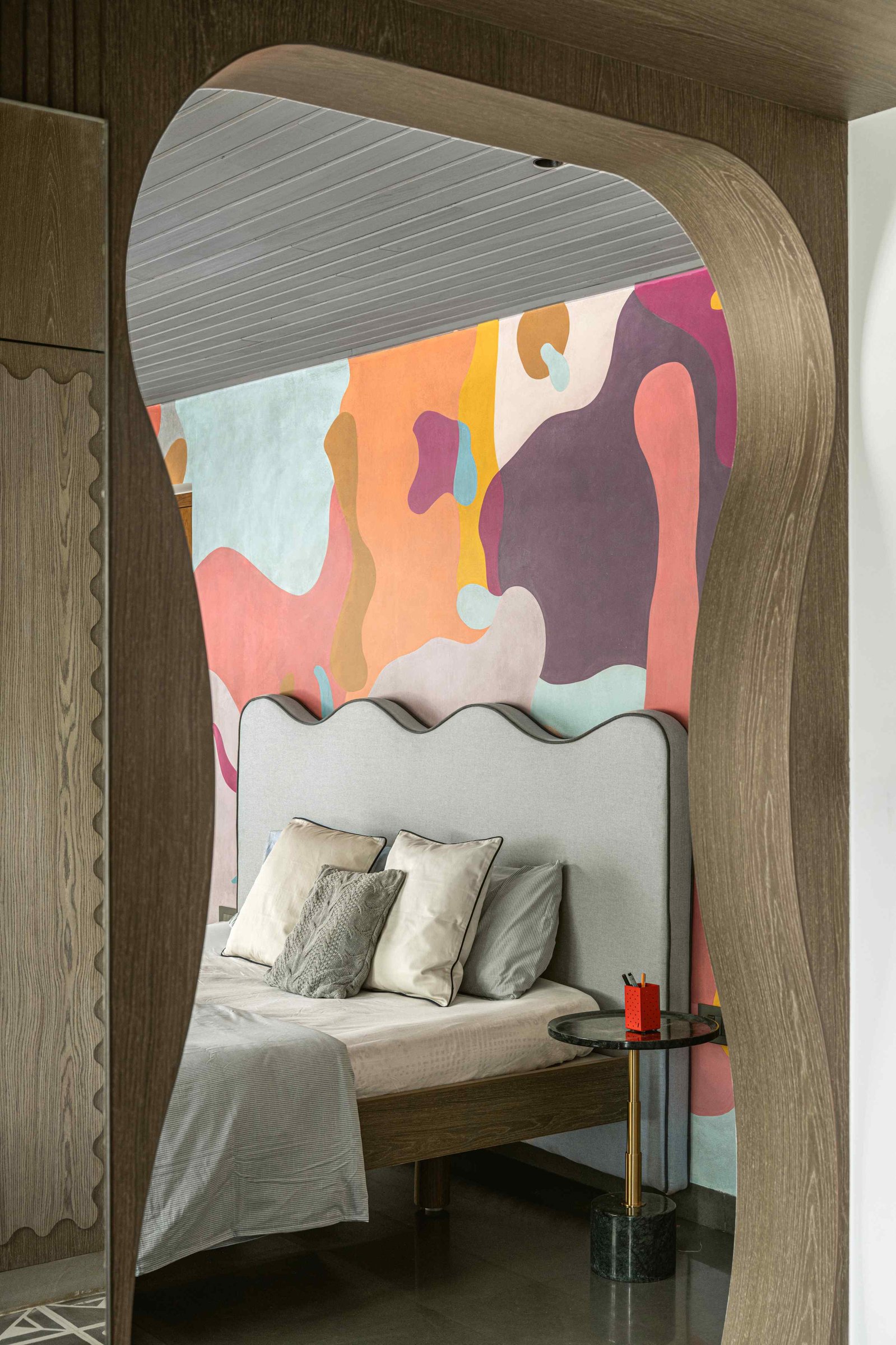 A sinuously carved oak arch frames the view into the bedroom, echoing the mural's organic forms