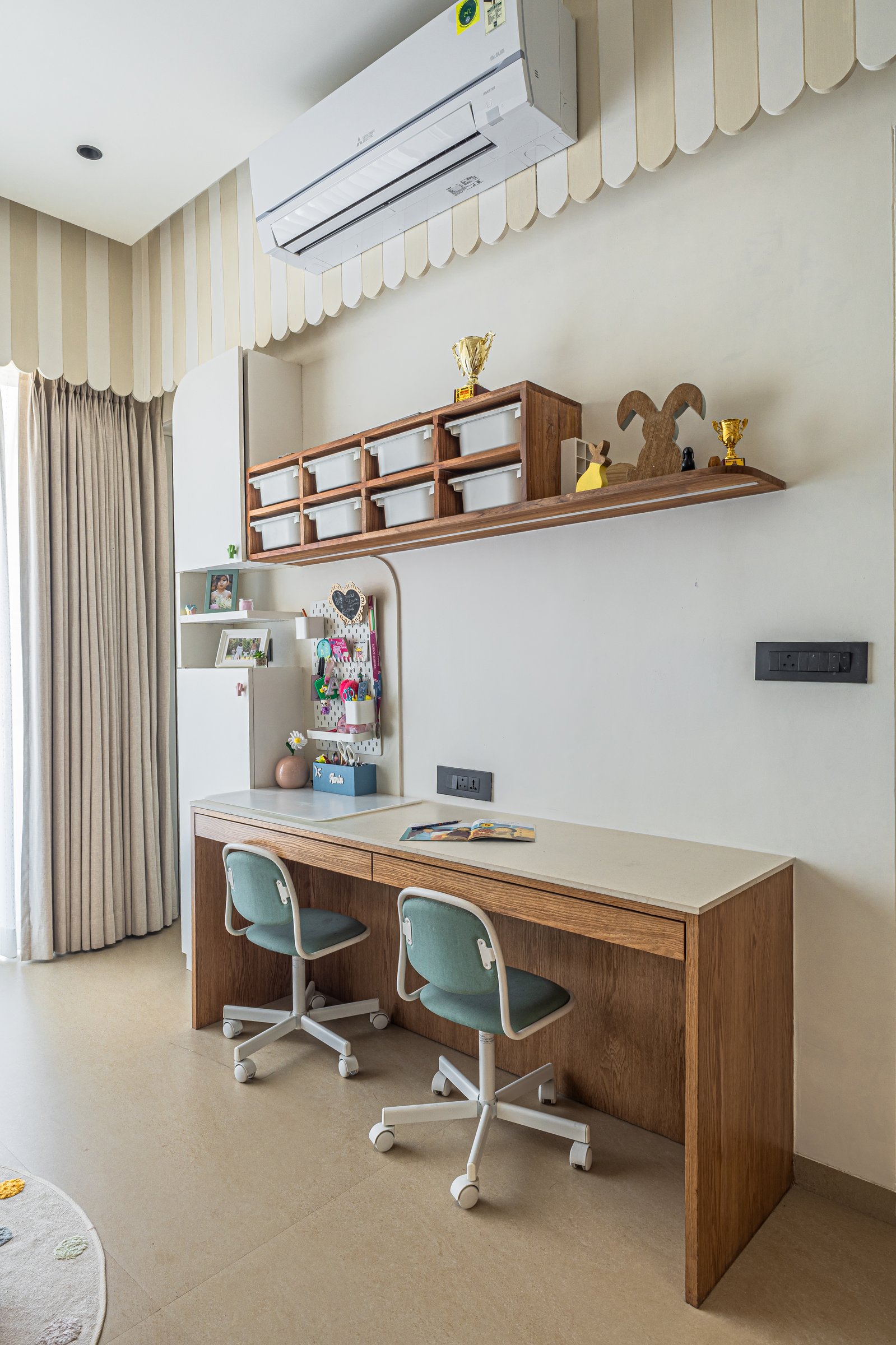 A study counter in warm wood with swivel chairs and labelled bins, designed for how the children will grow into the room