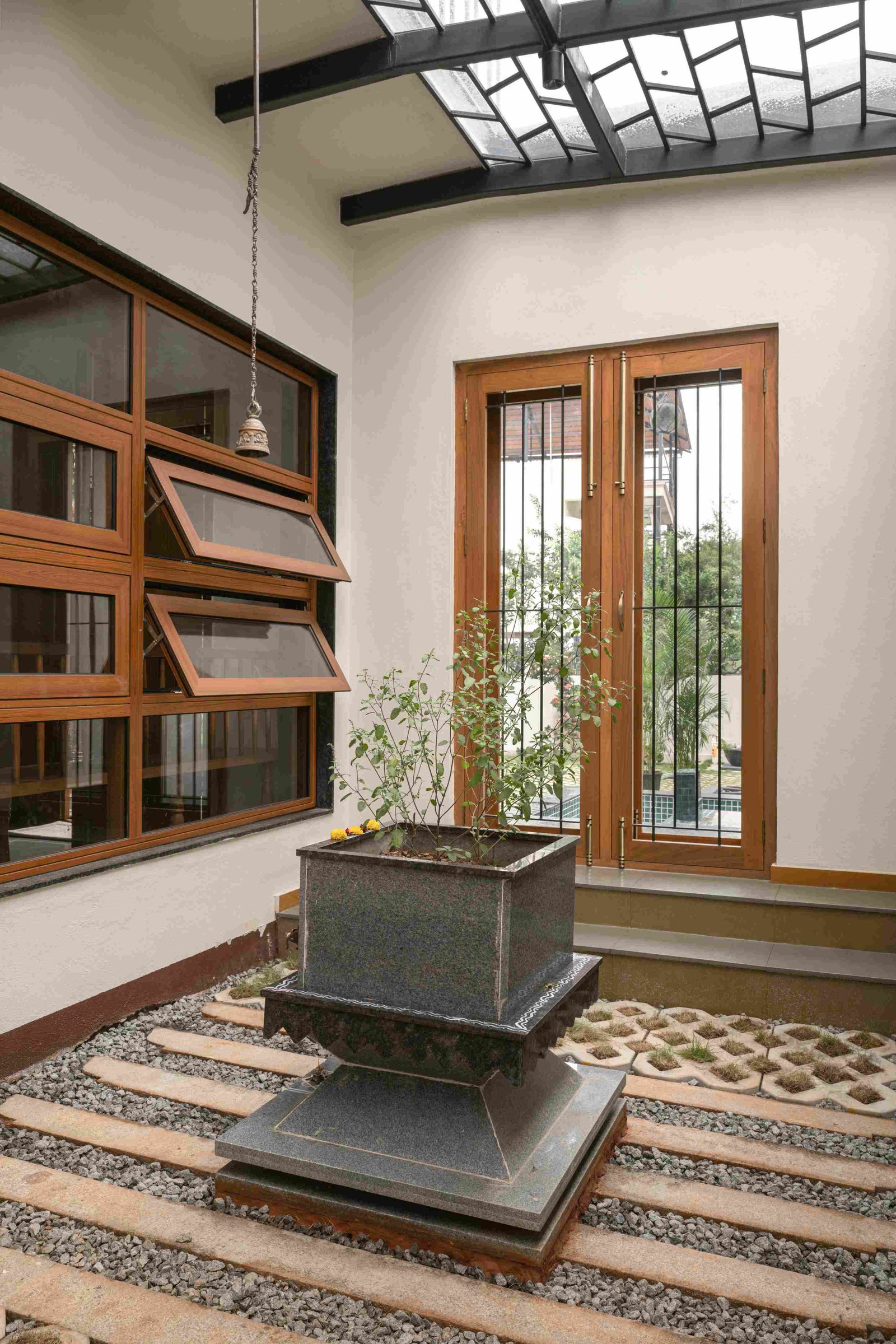 An internal courtyard with a tulasi shrine at its centre, lit through a patterned steel skylight