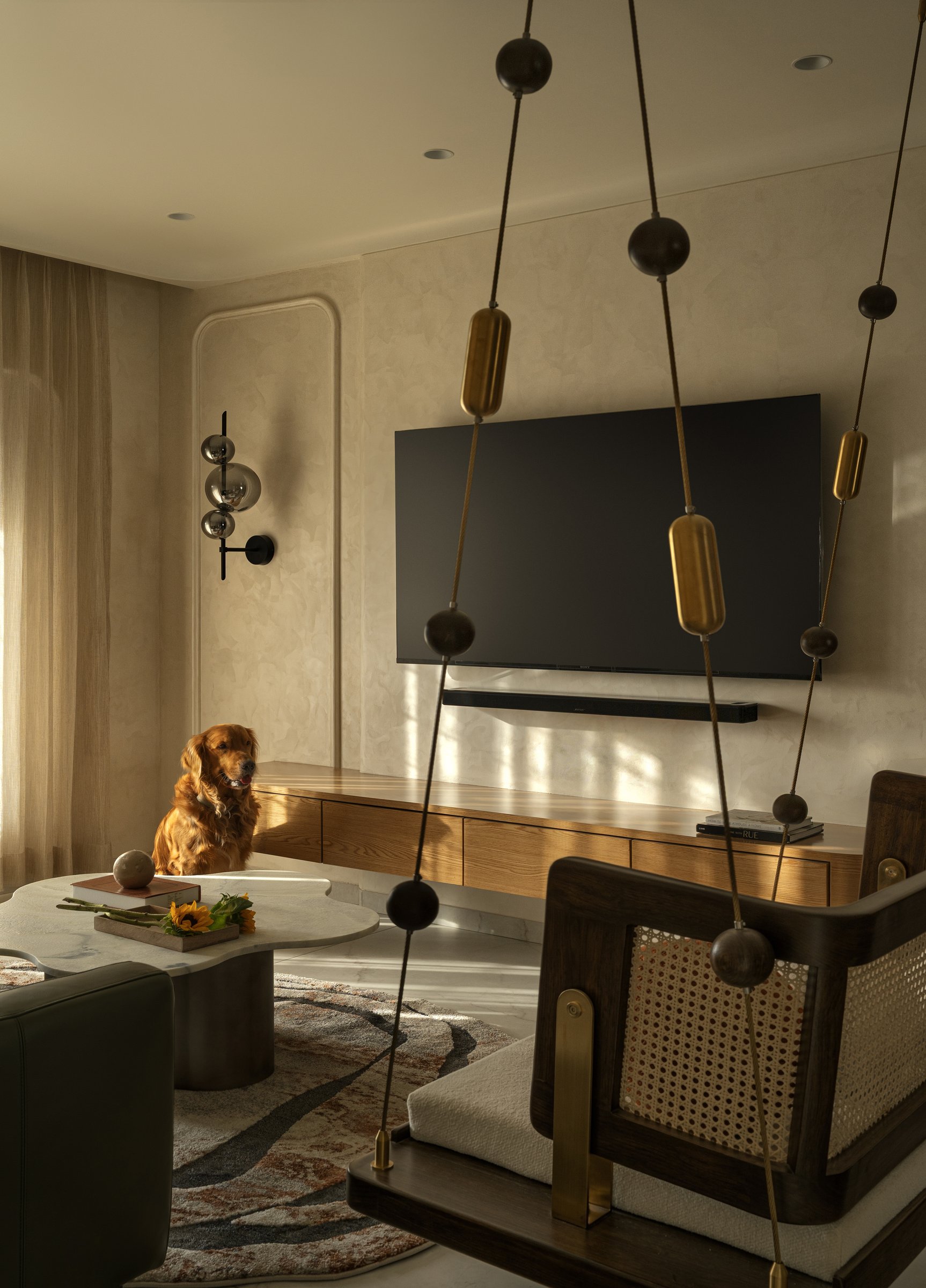 The media wall, where restraint extends even to the television, anchored by a long oak console and a single smoked-glass sconce