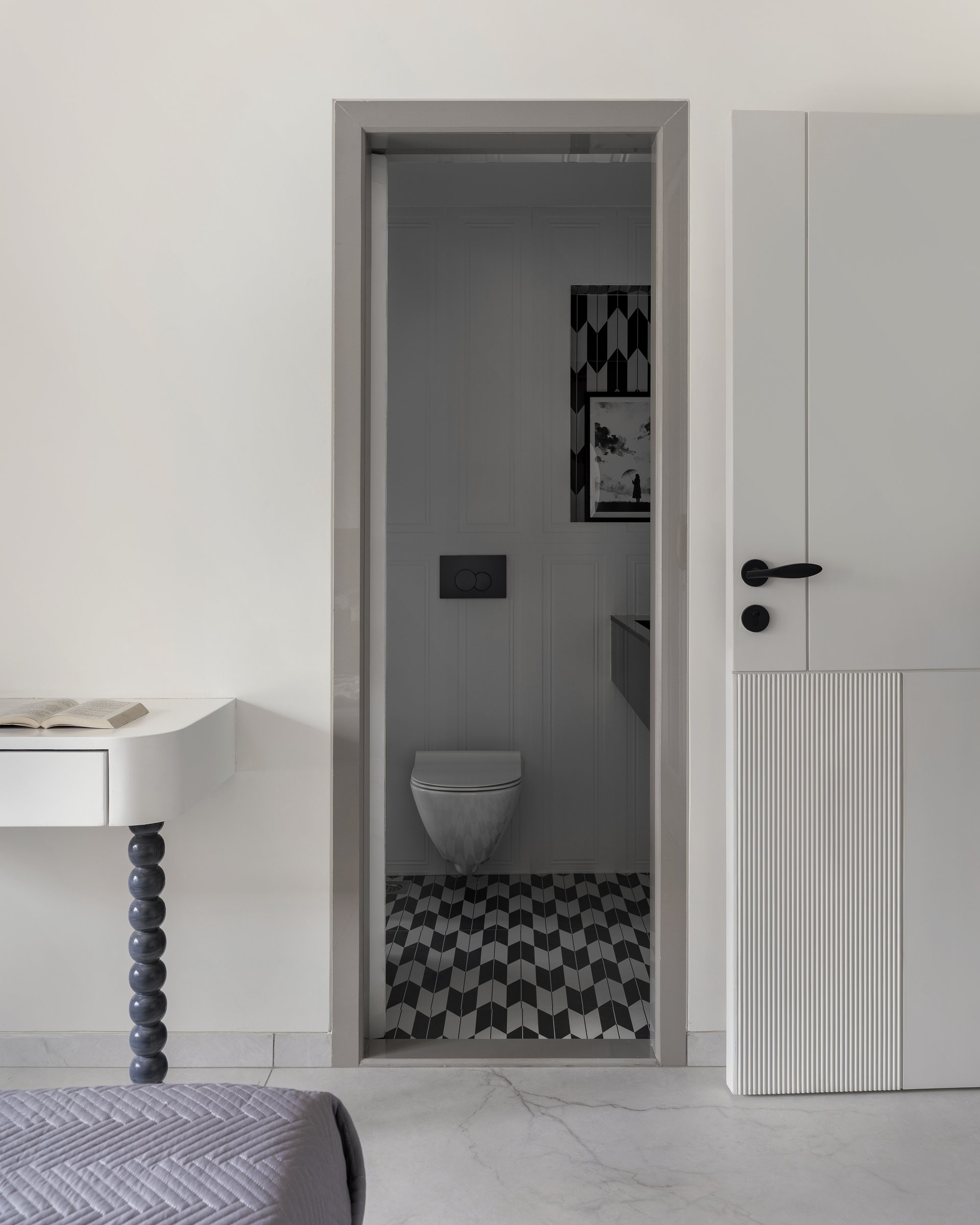 Through the doorway, the attached bathroom reveals the home's sharpest tonal pivot in a chevron floor of black and white