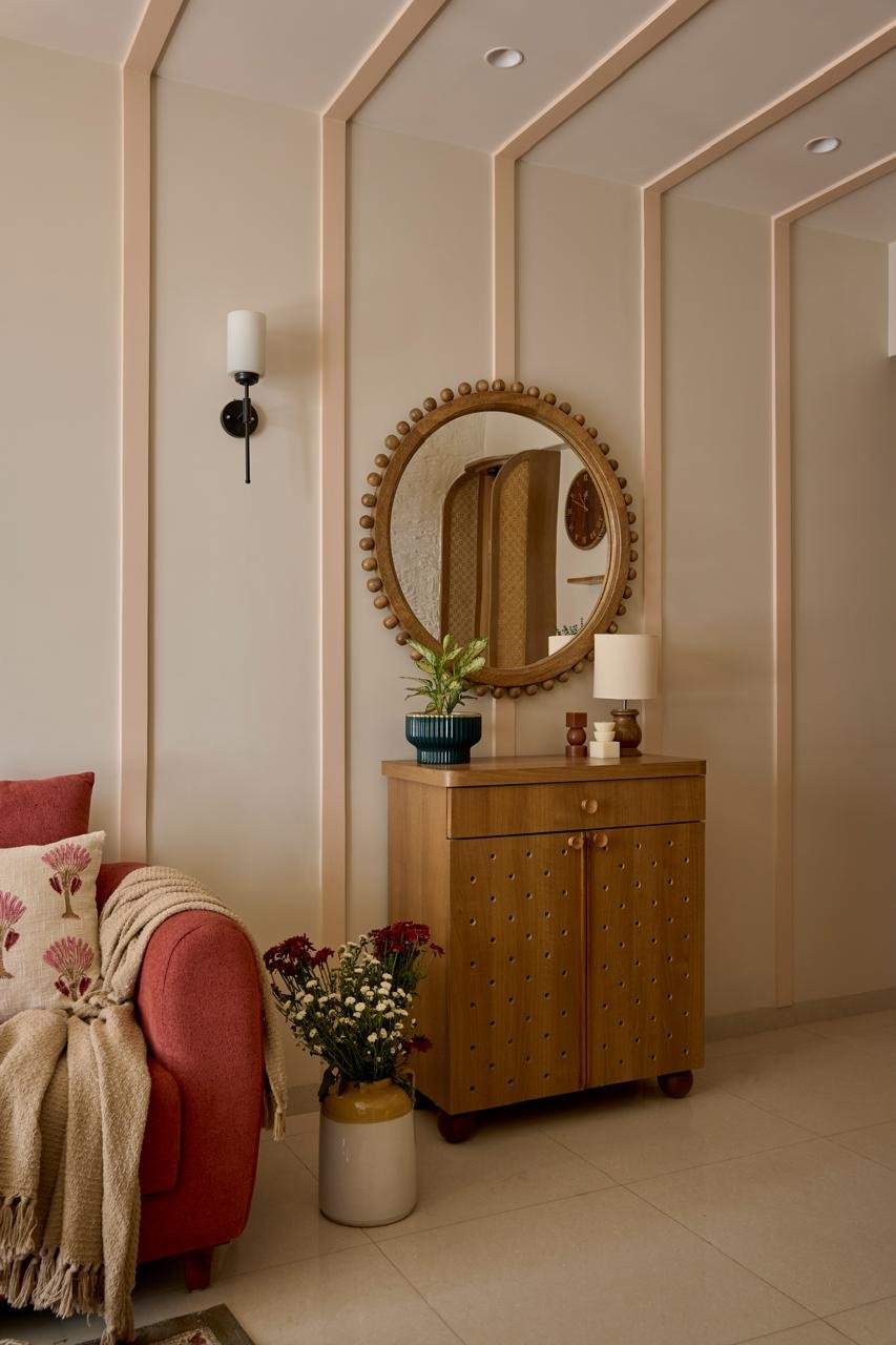 The foyer, where peach-toned slats fold from wall to ceiling in a quiet waterfall and a beaded round mirror sets the home's curved vocabulary