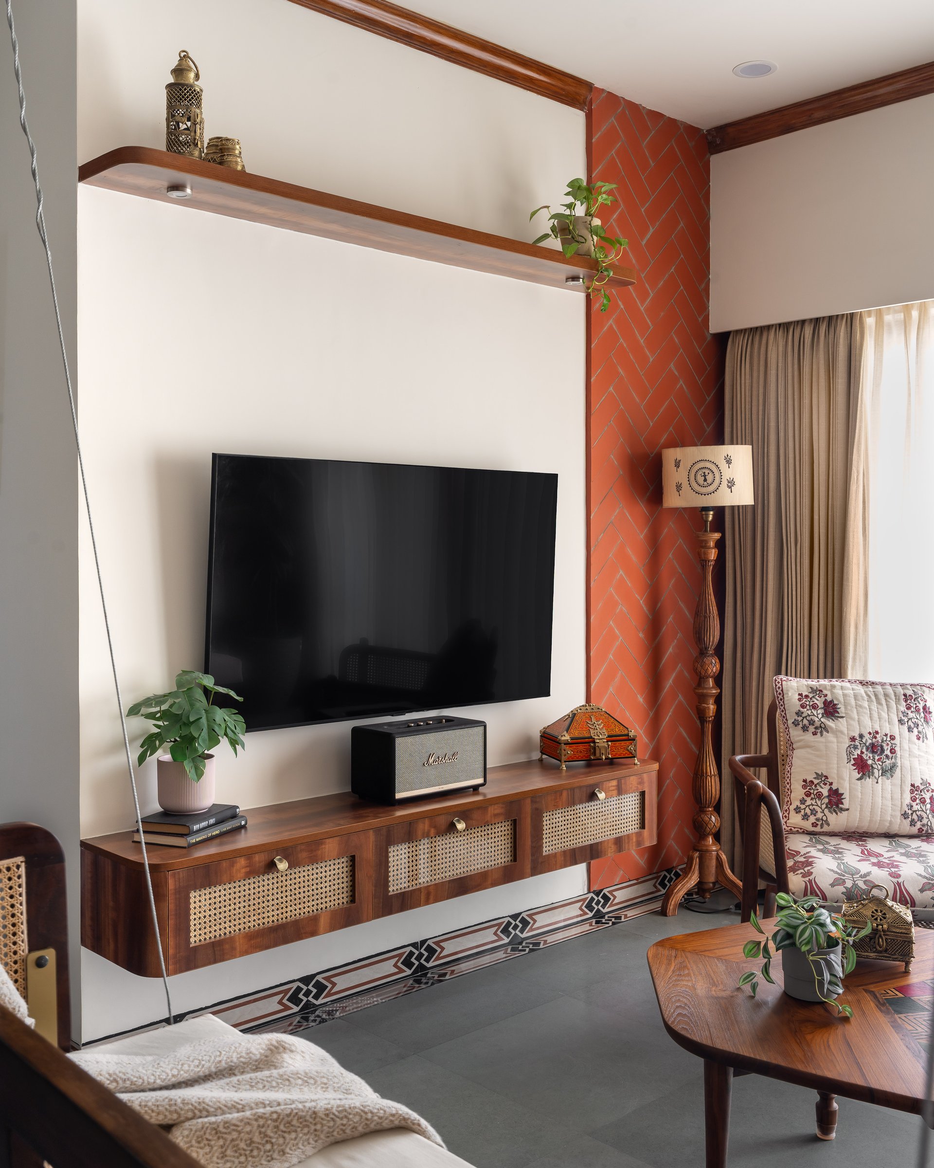 The herringbone brick column and cane-fronted media console, tied together by the home's signature patterned-cement skirting