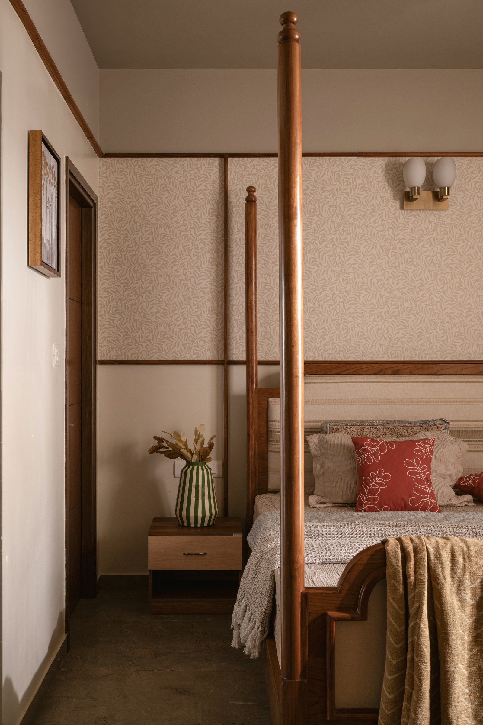 The same bedroom from the foot of the bed, where wooden mouldings and warm bedding hold the room in a lived-in register