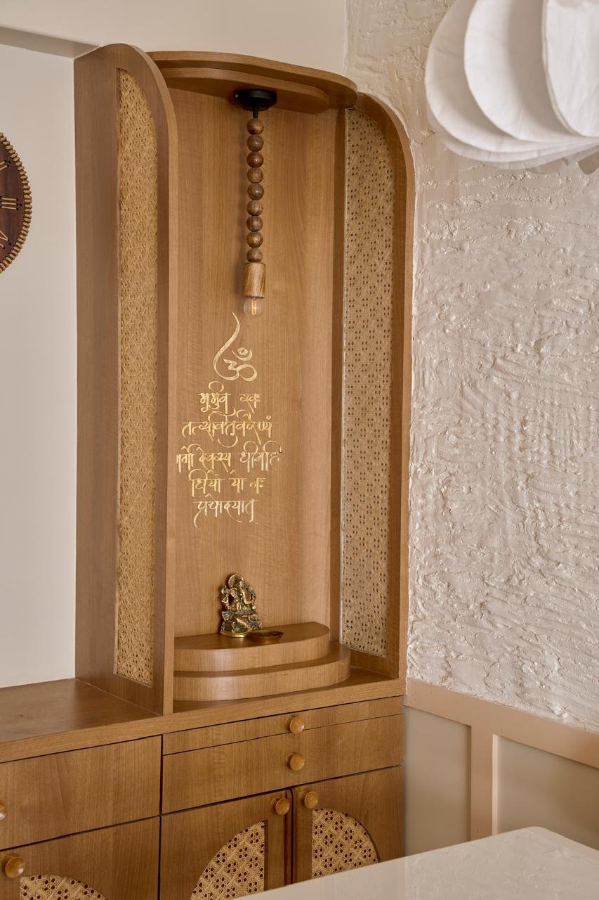 The built-in pooja niche, framed in cane and carrying a gilt-inscribed Sanskrit shloka