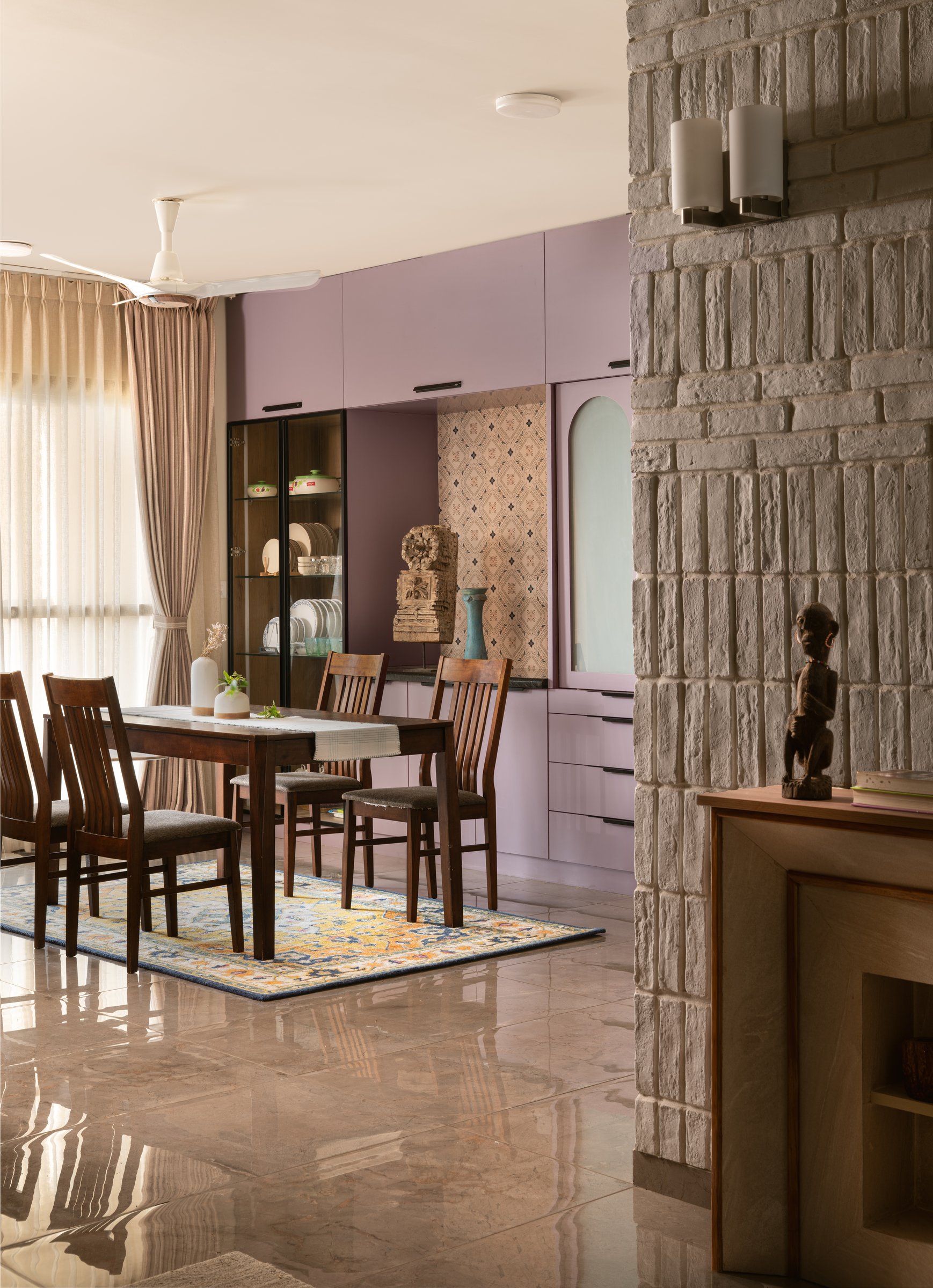 The dining area, where a pale mauve crockery wall and a pale grey masonry wall hold the home's most unexpected adjacency