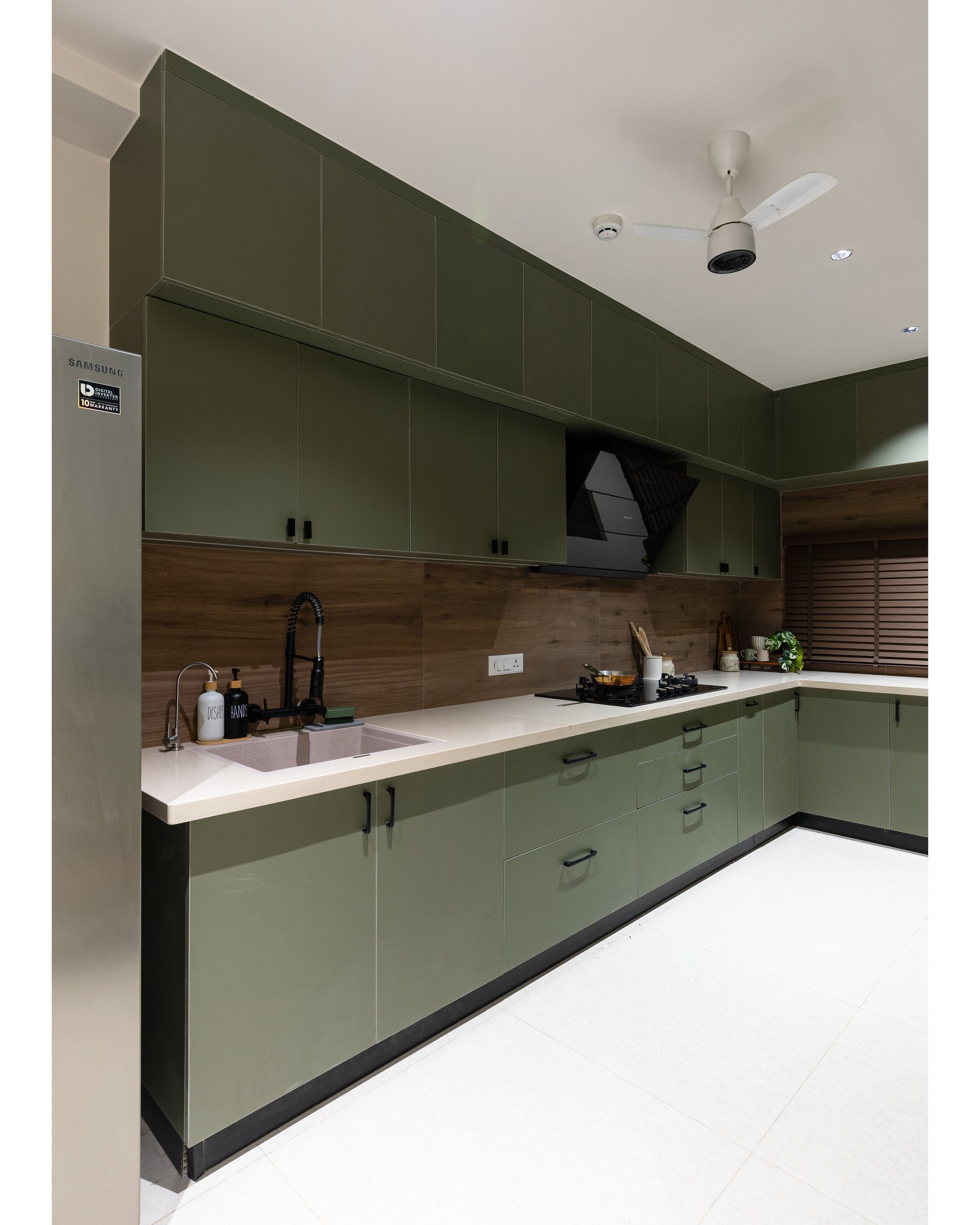 The kitchen in olive-green high-gloss cabinetry, its colour pulling the public area's upholstery into the working room