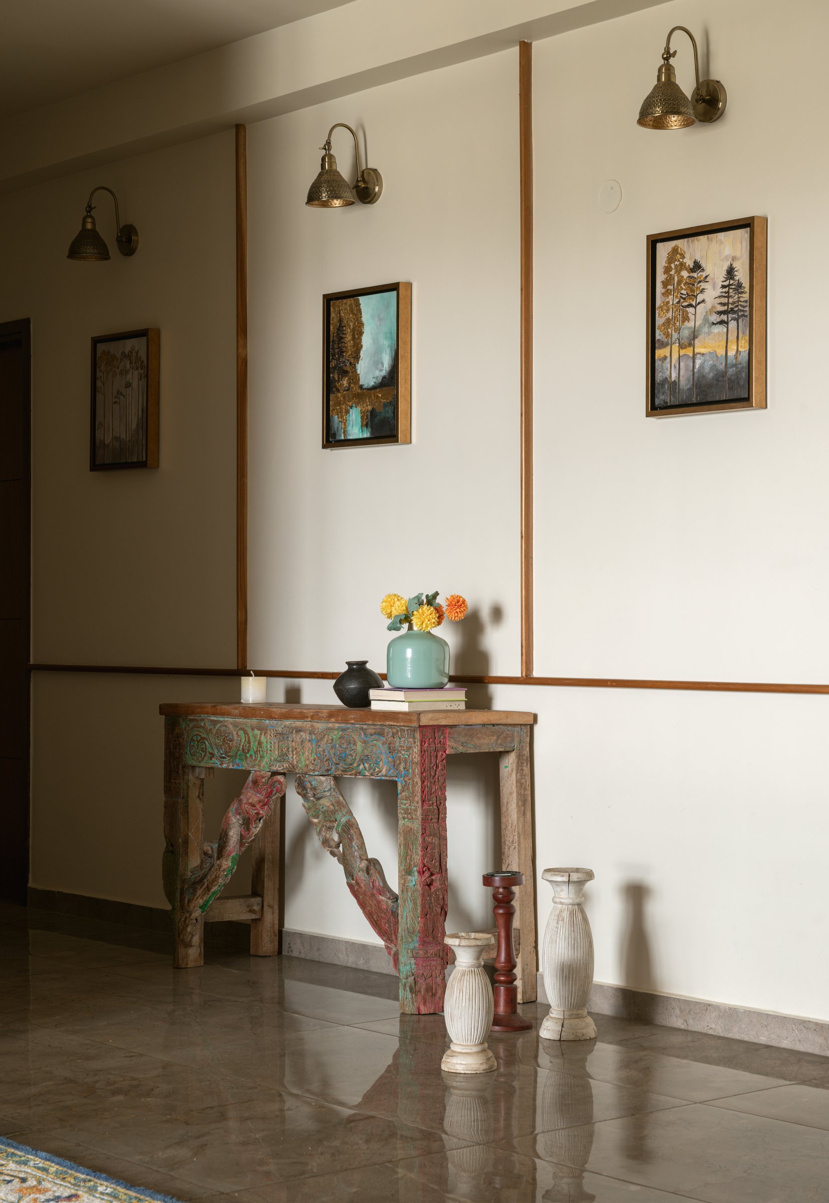 The foyer console in reclaimed wood, where the home's refusal to belong to a single palette is announced before any room is entered