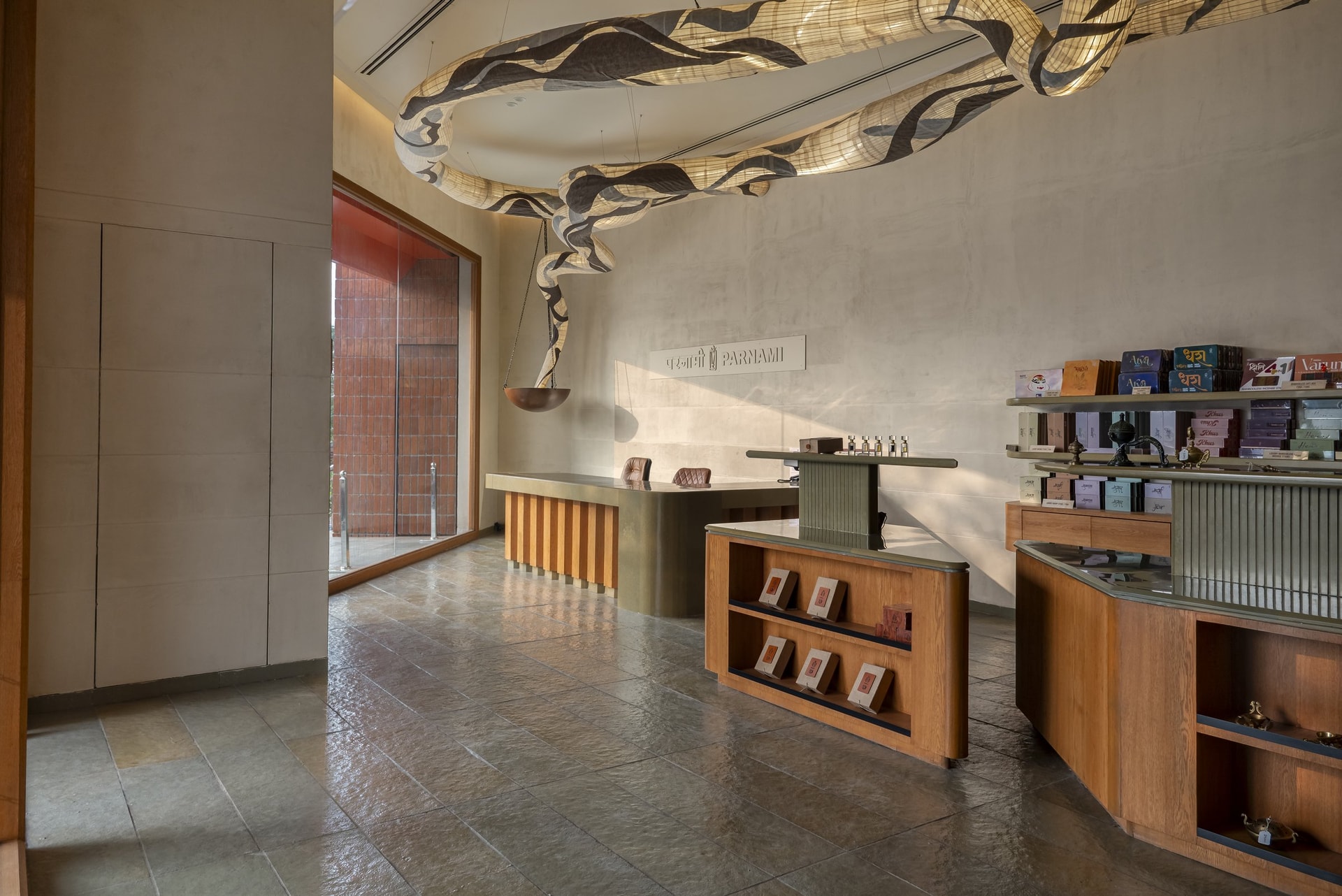 The long counter in fluted oak meets the Parnami wordmark on a pale stone-textured wall