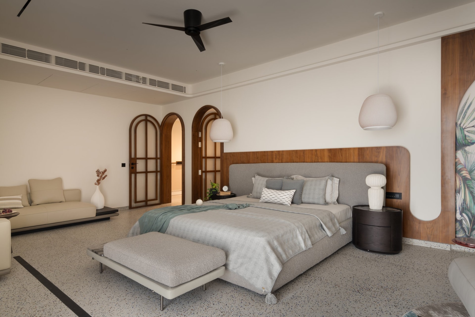 The master bedroom, where a curved walnut headboard wall and two arched doors set the proportions