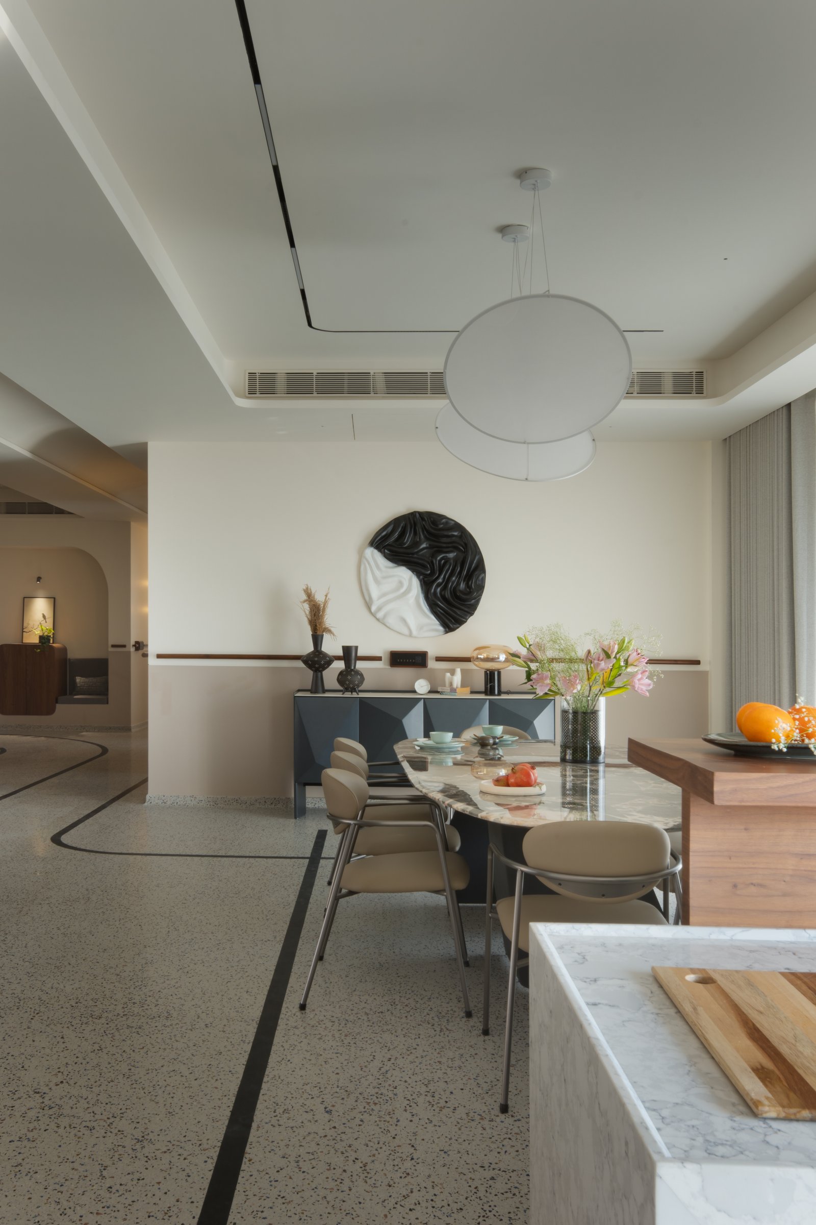 The dining area, anchored by a marble-topped oval table and a faceted sideboard