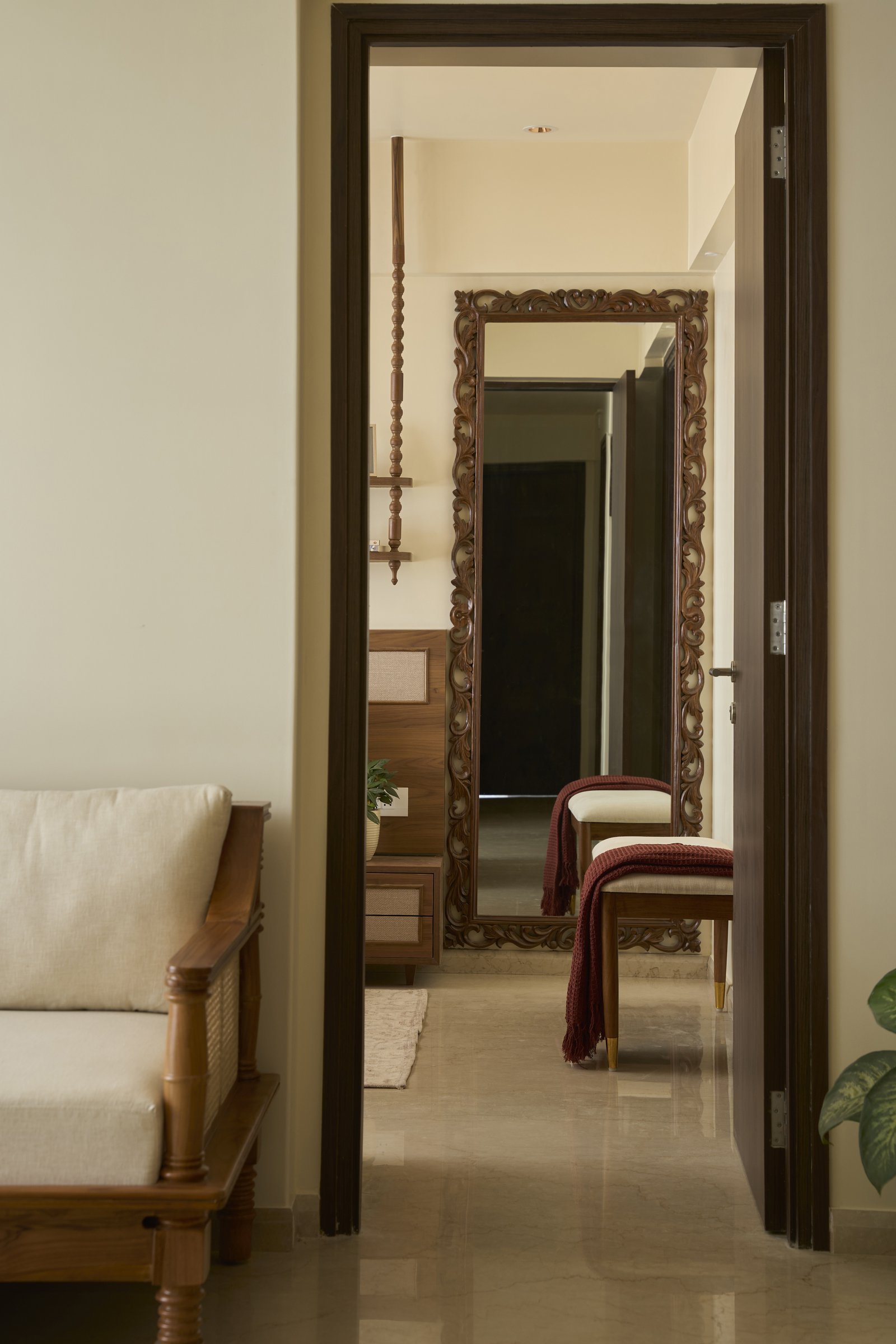 The passage to the master bedroom, where a carved wood mirror extends the home's linear axis and doubles the available light