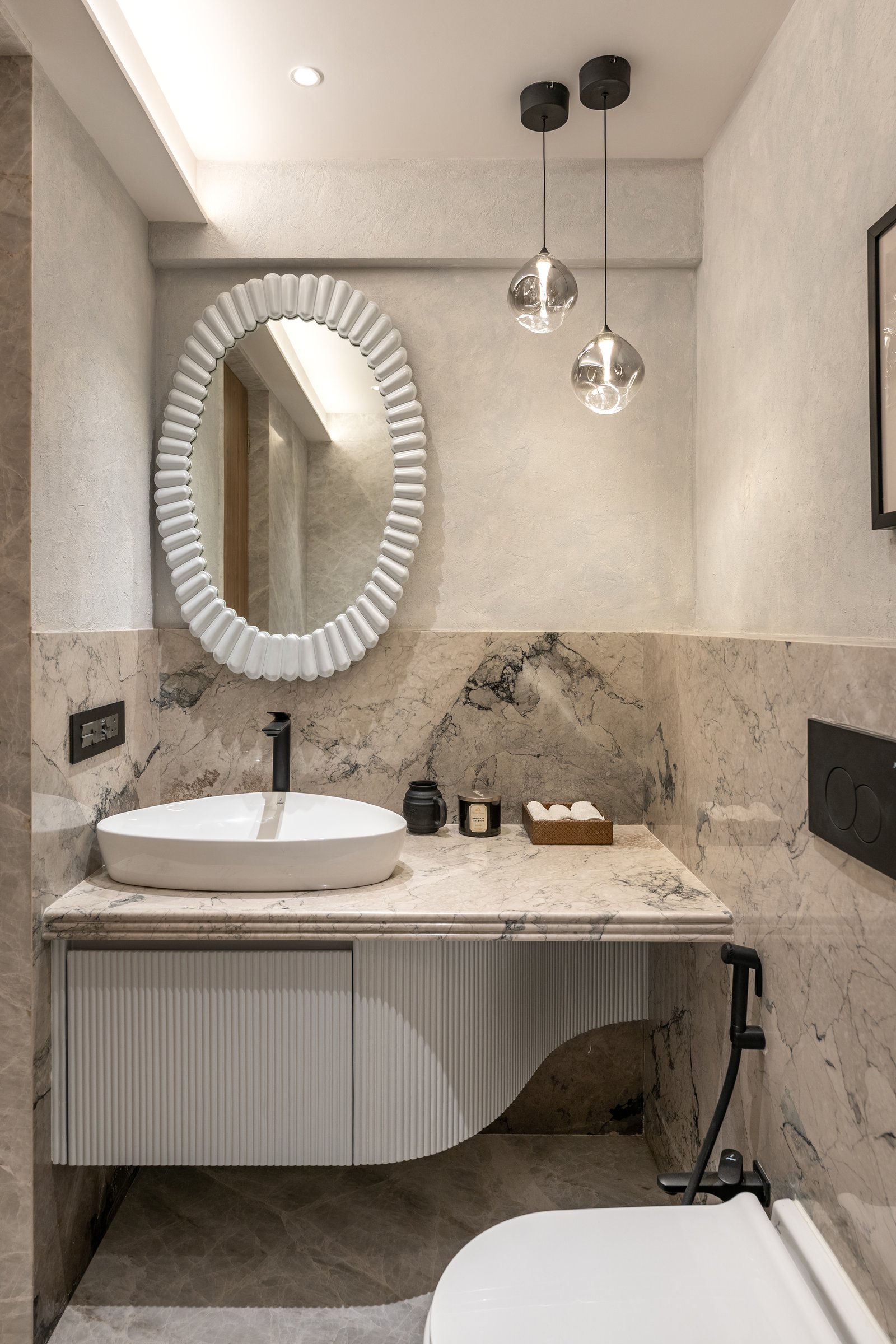 The powder room: a scalloped oval mirror above a dramatically veined stone counter
