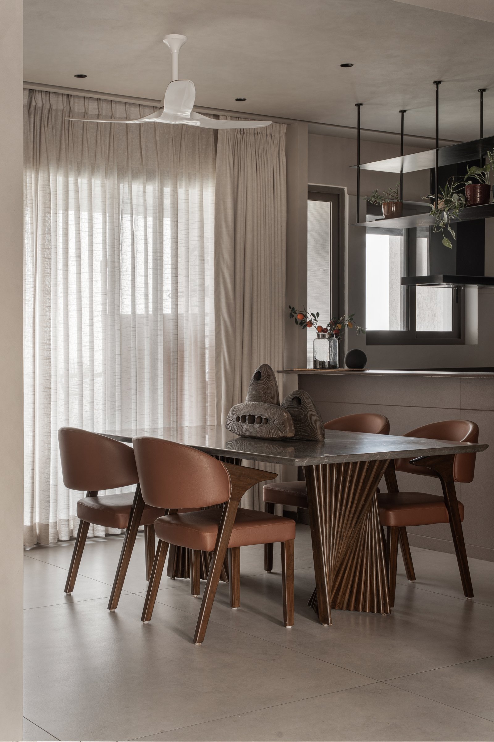 The dining area, anchored by a stone-topped table on a fan-pleated wooden base