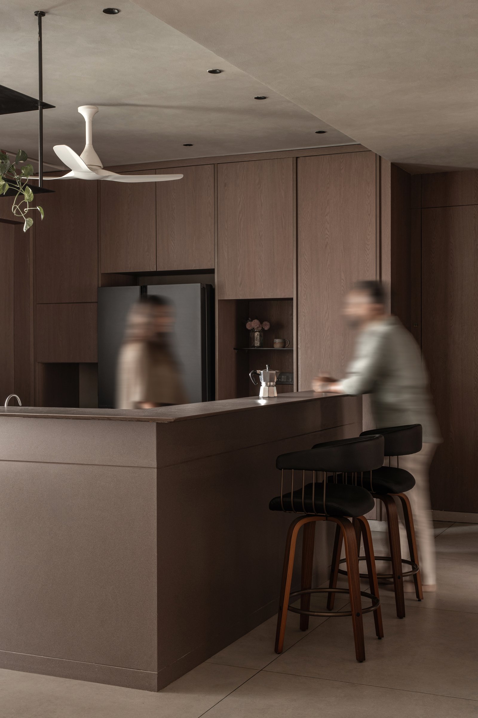 The kitchen: flush wood paneling absorbs every appliance and storage zone into a single continuous surface