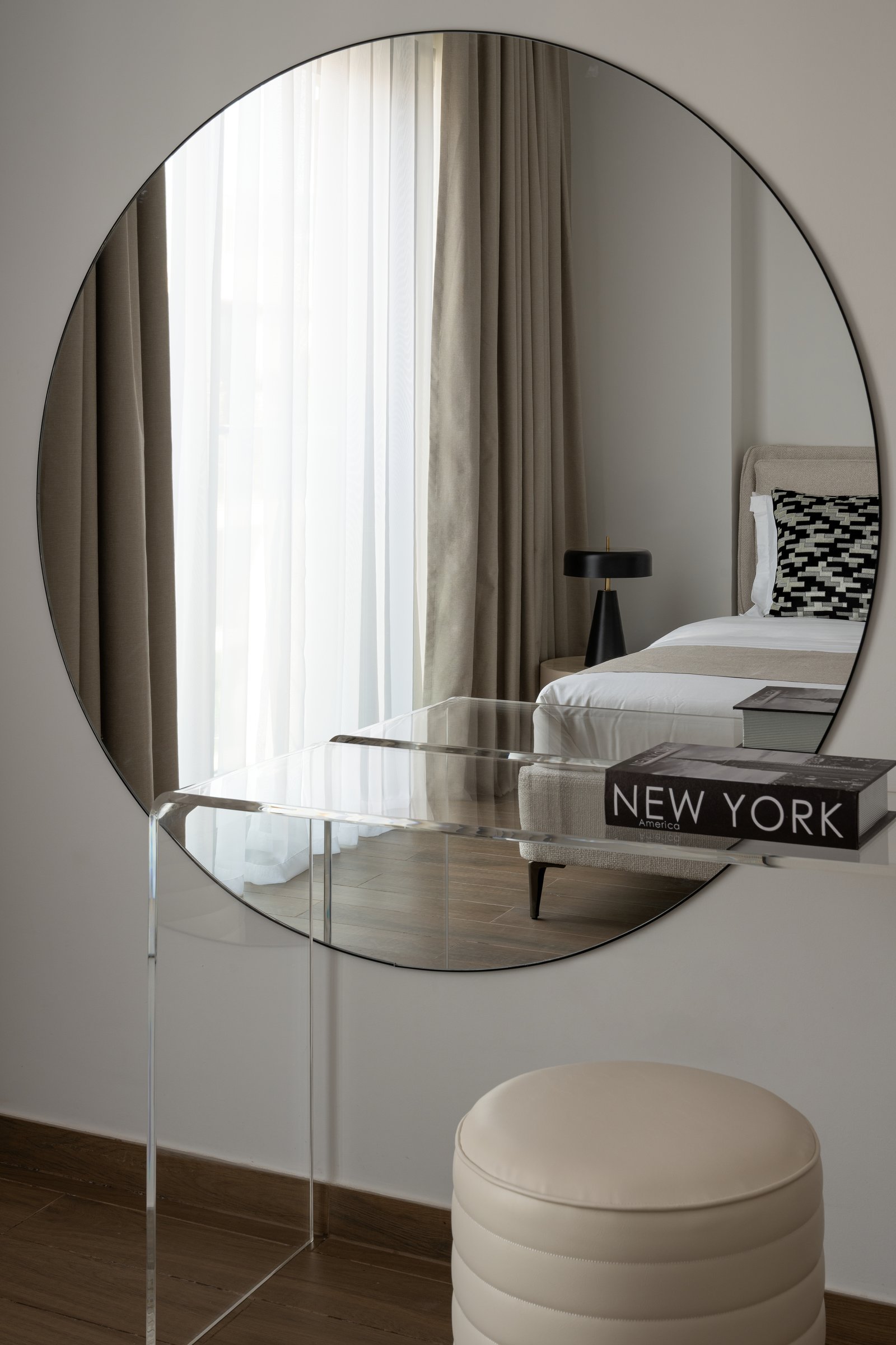 An acrylic console beneath a large circular mirror, a dressing corner that occupies almost no visual space