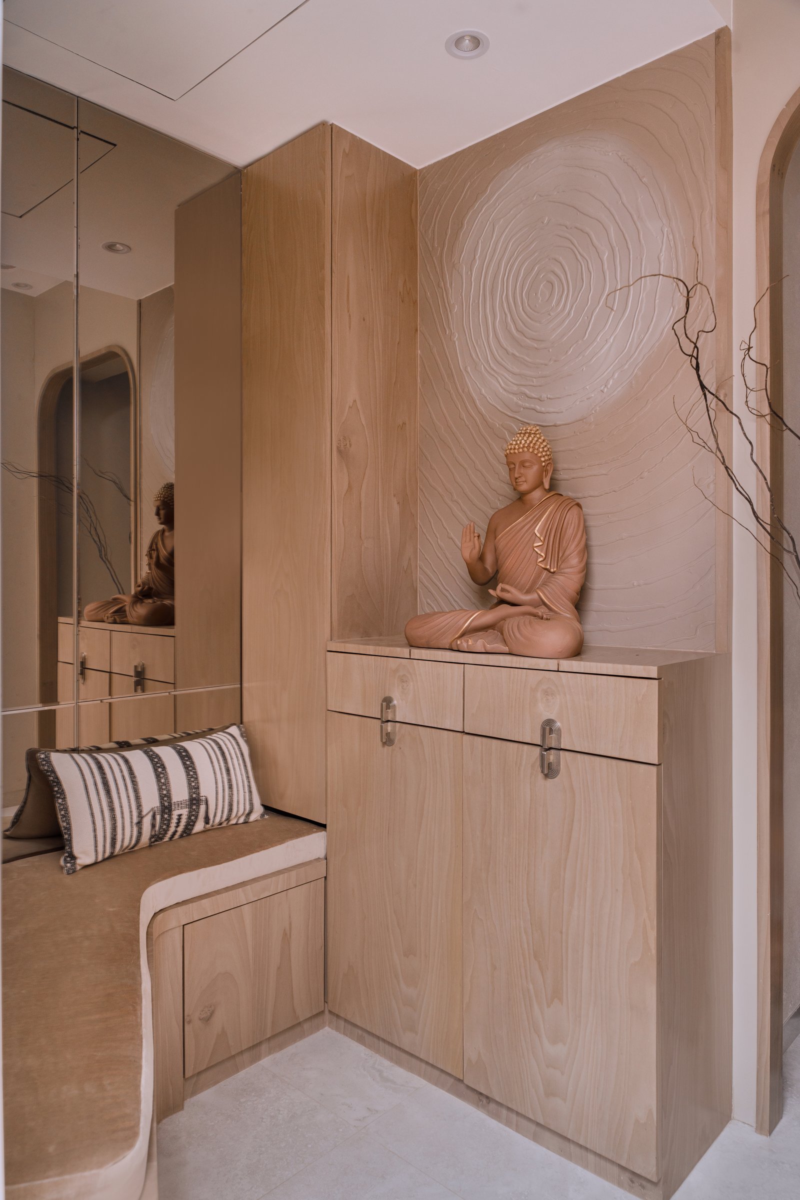 The foyer, where a rippled plaster relief and a pale wood console set the home's meditative tone