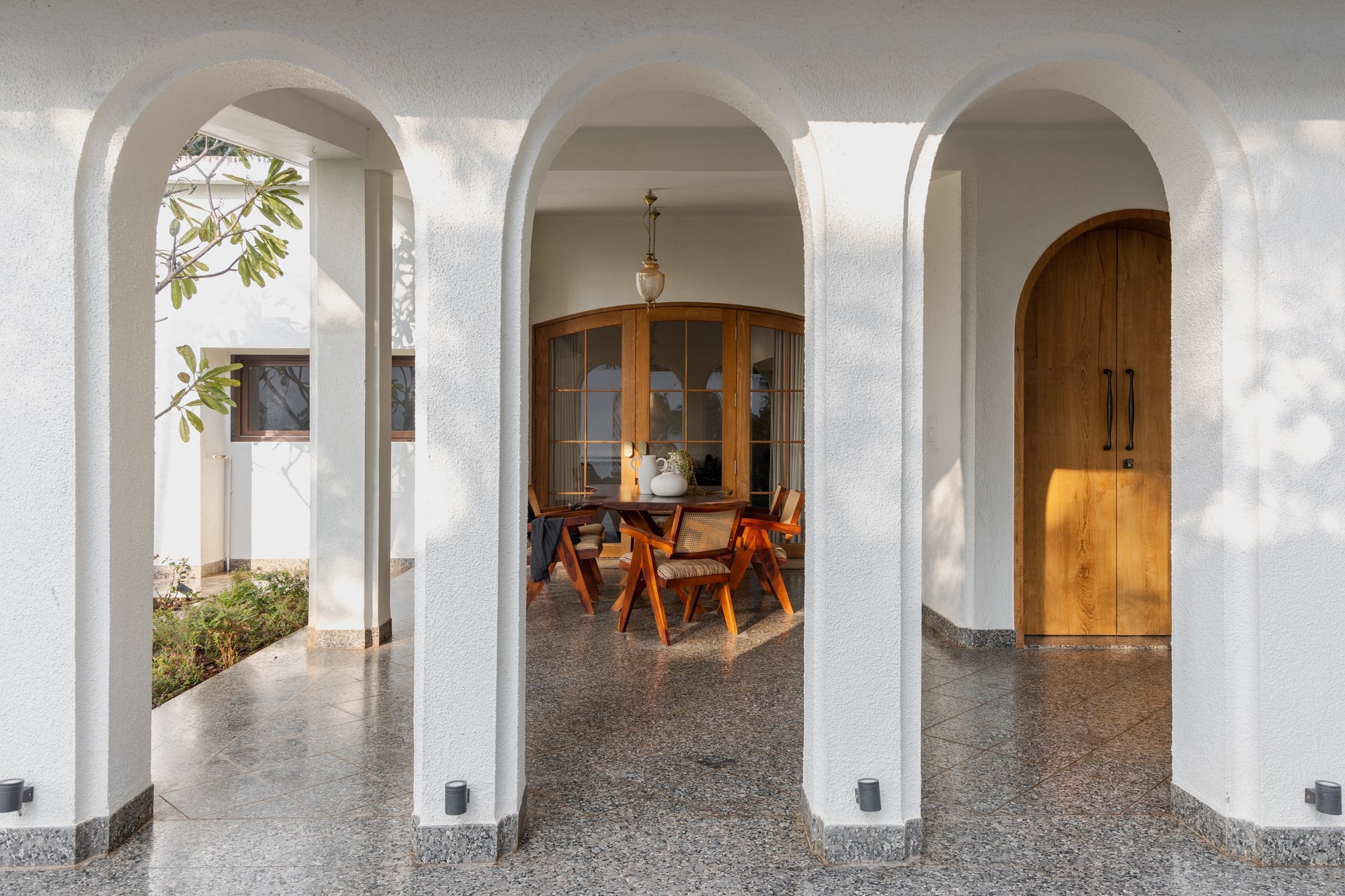 Three full-height arches set the tone of the approach, framing the dining beyond with cloistered stillness