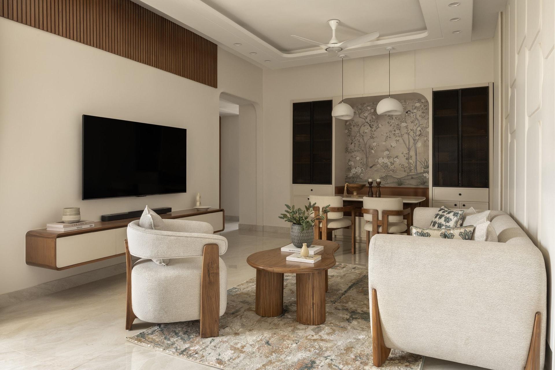 The living room, opening into a dining nook framed by a chinoiserie panel and tall reeded-glass cabinets