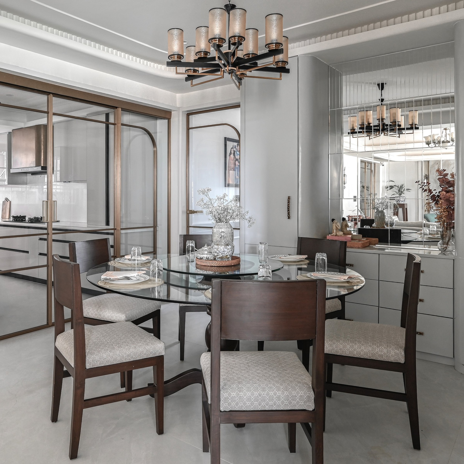 The dining room, framed by a brass-and-glass partition that reads as architecture rather than screen