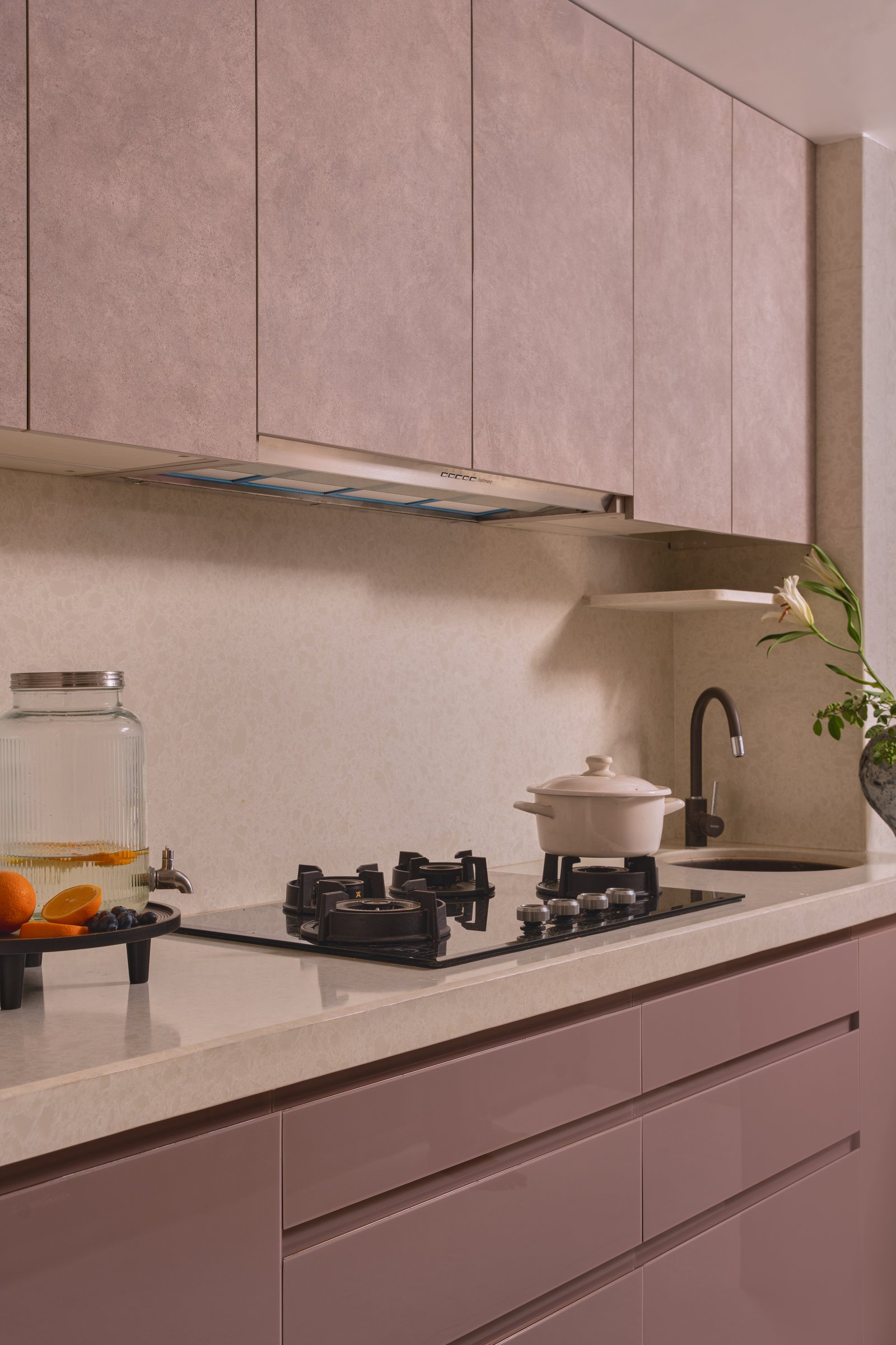At the cooking counter, pale stone keeps the room visually weightless against the rose cabinetry