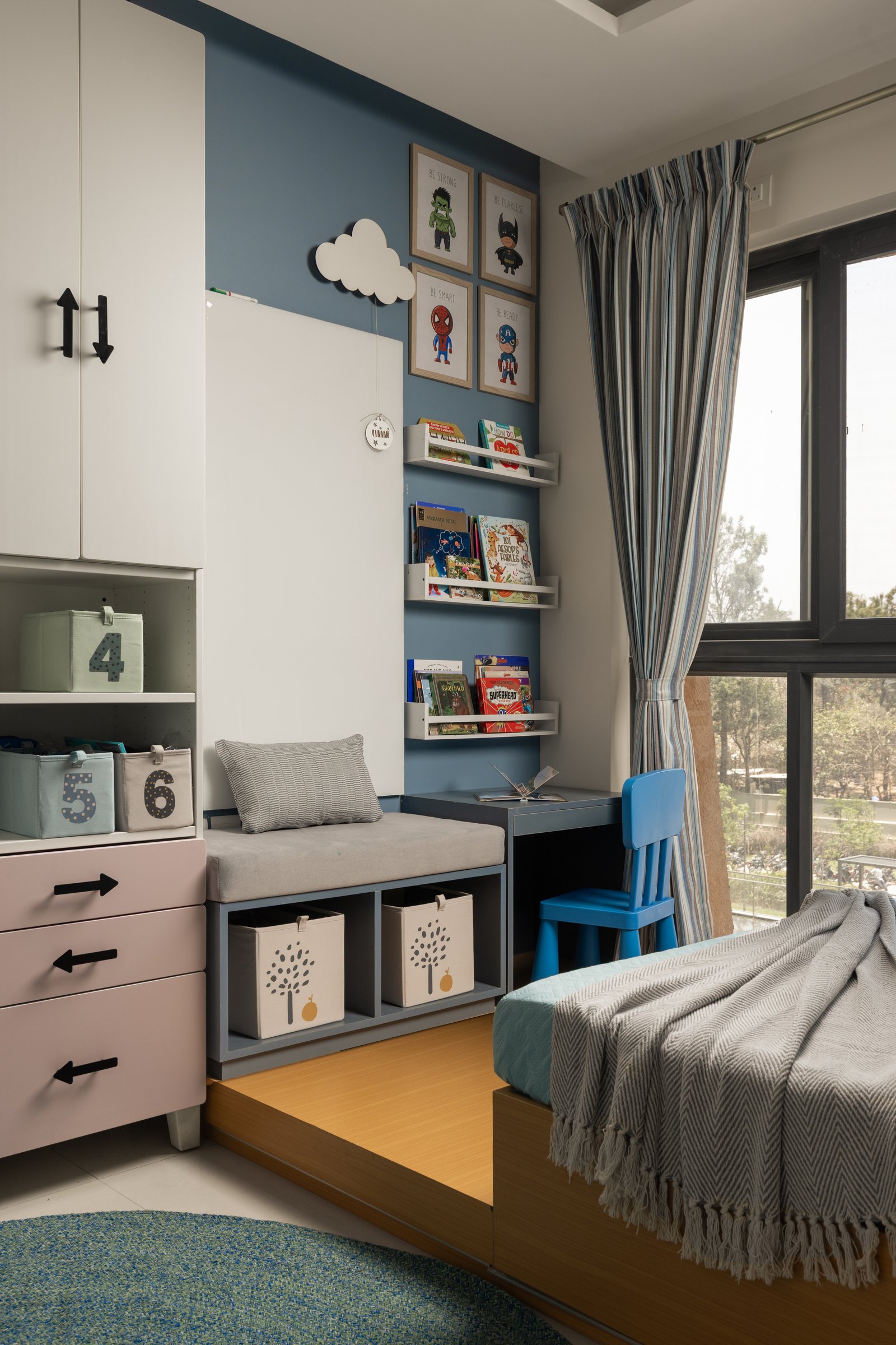 The study corner, where colour-blocked drawers, a window seat and a grid of superhero prints argue for disciplined imagination